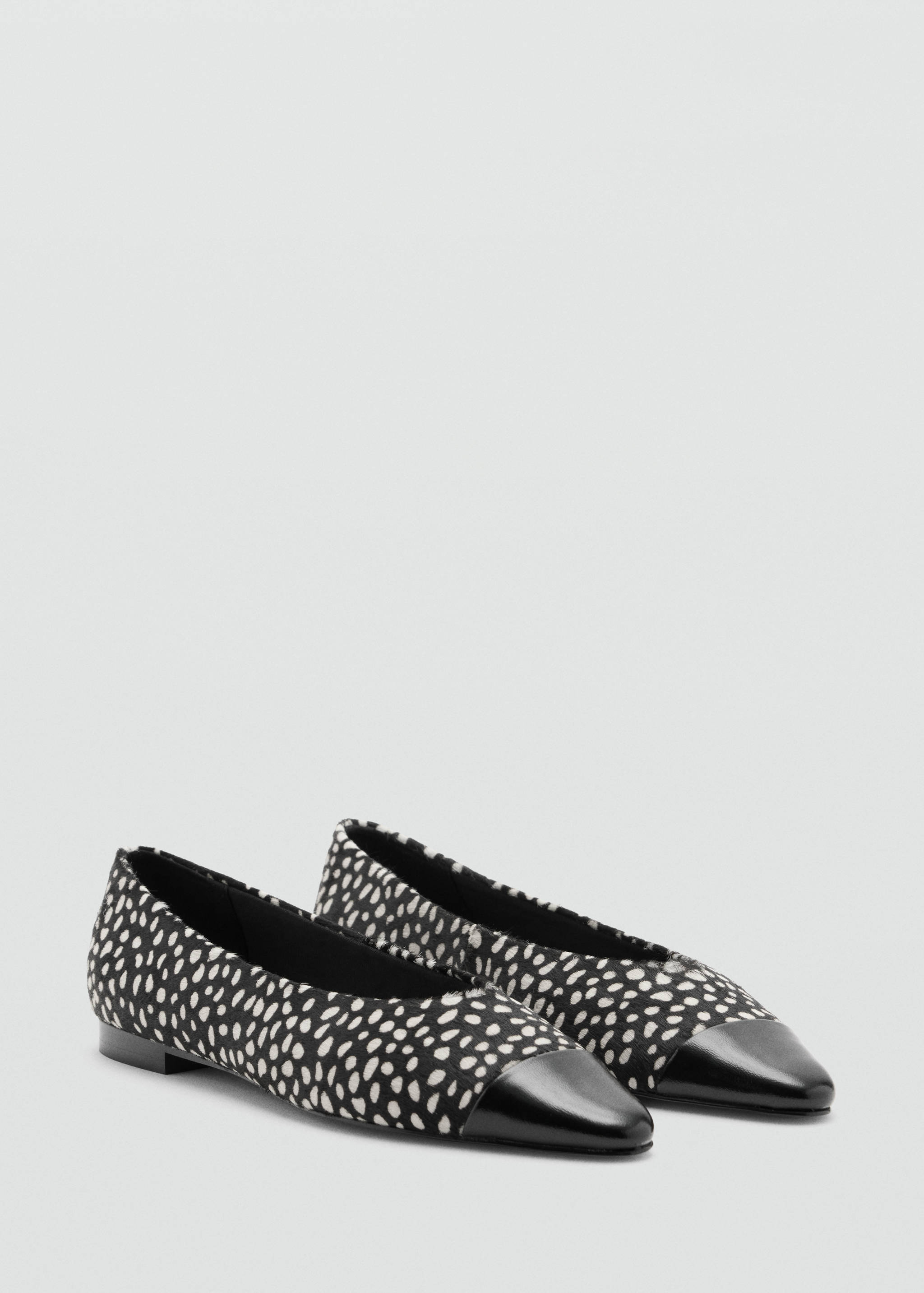 Black and white spotted flat shoes with black toe caps.