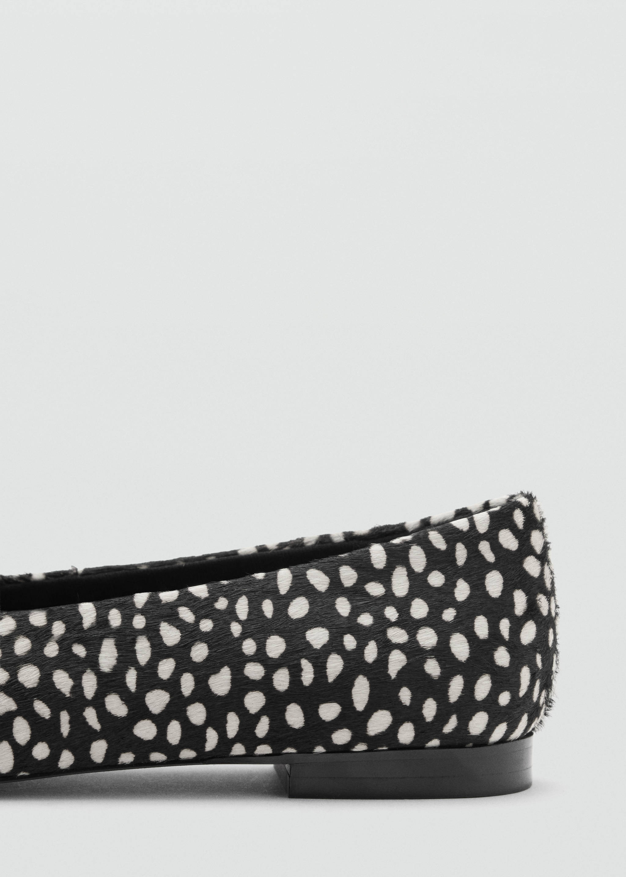 Close-up of a black and white animal-print flat shoe.