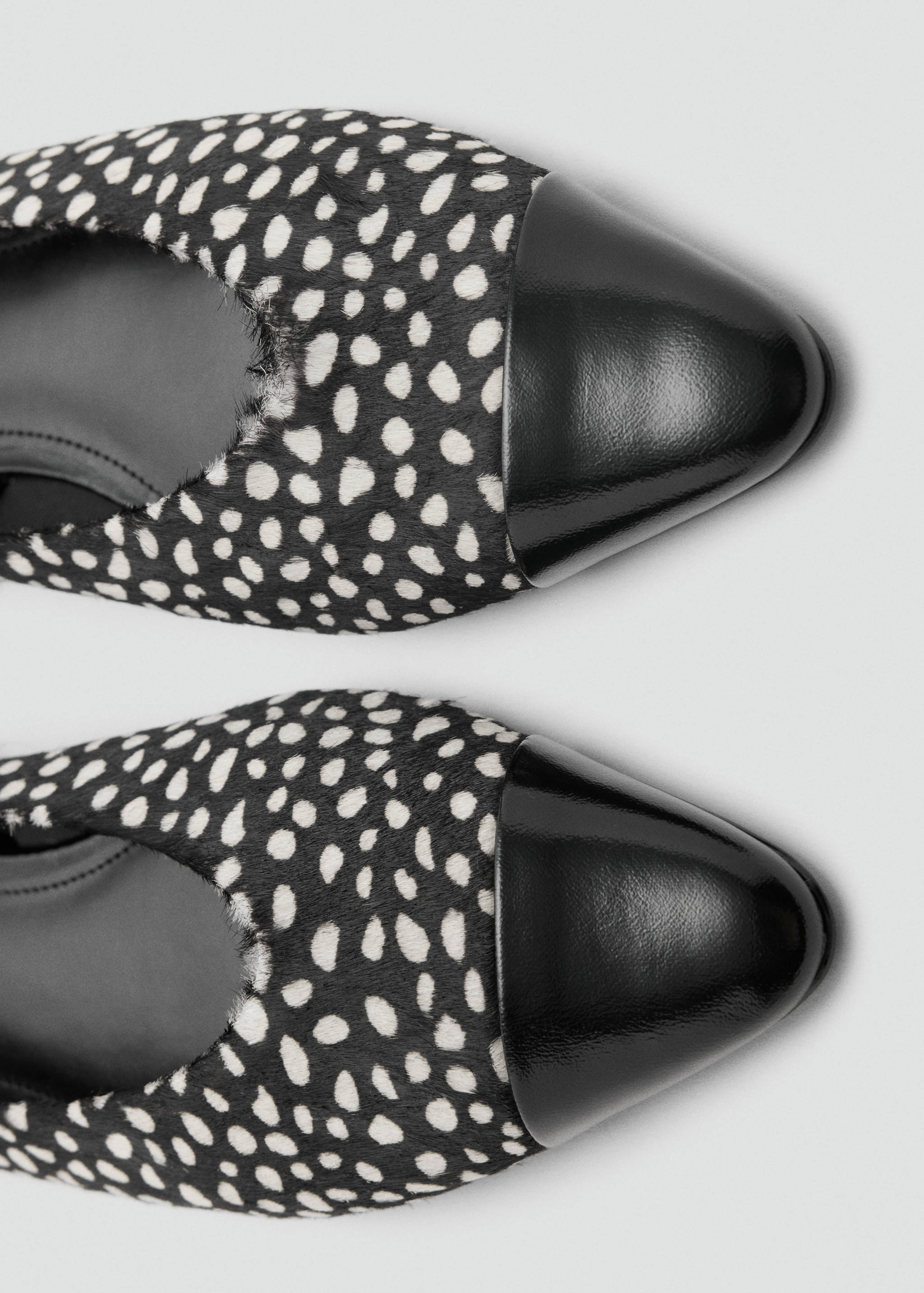Close-up of black and white animal print faux-fur shoes with black patent toe caps.