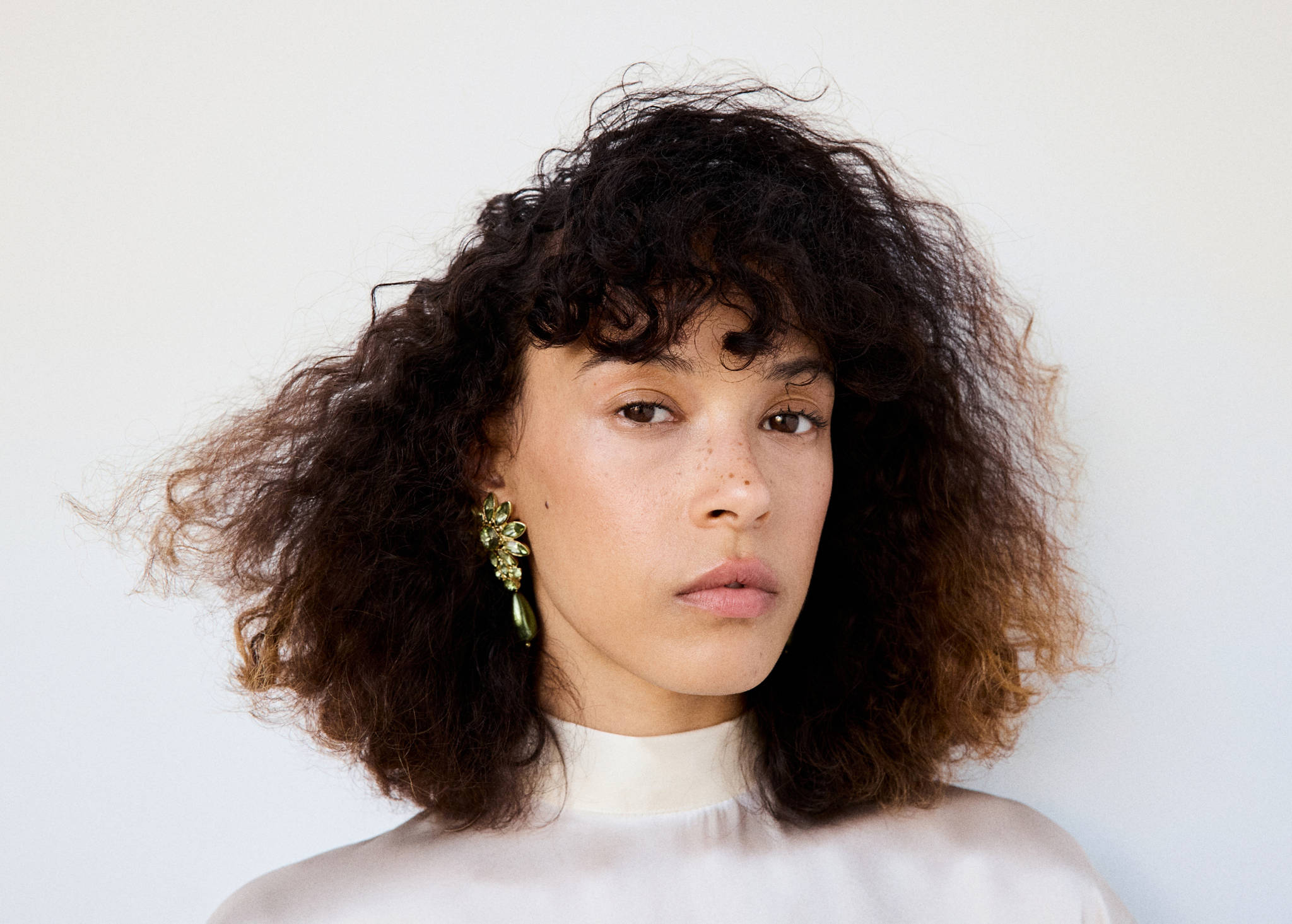 Green crystal cluster drop earring worn by a model.
