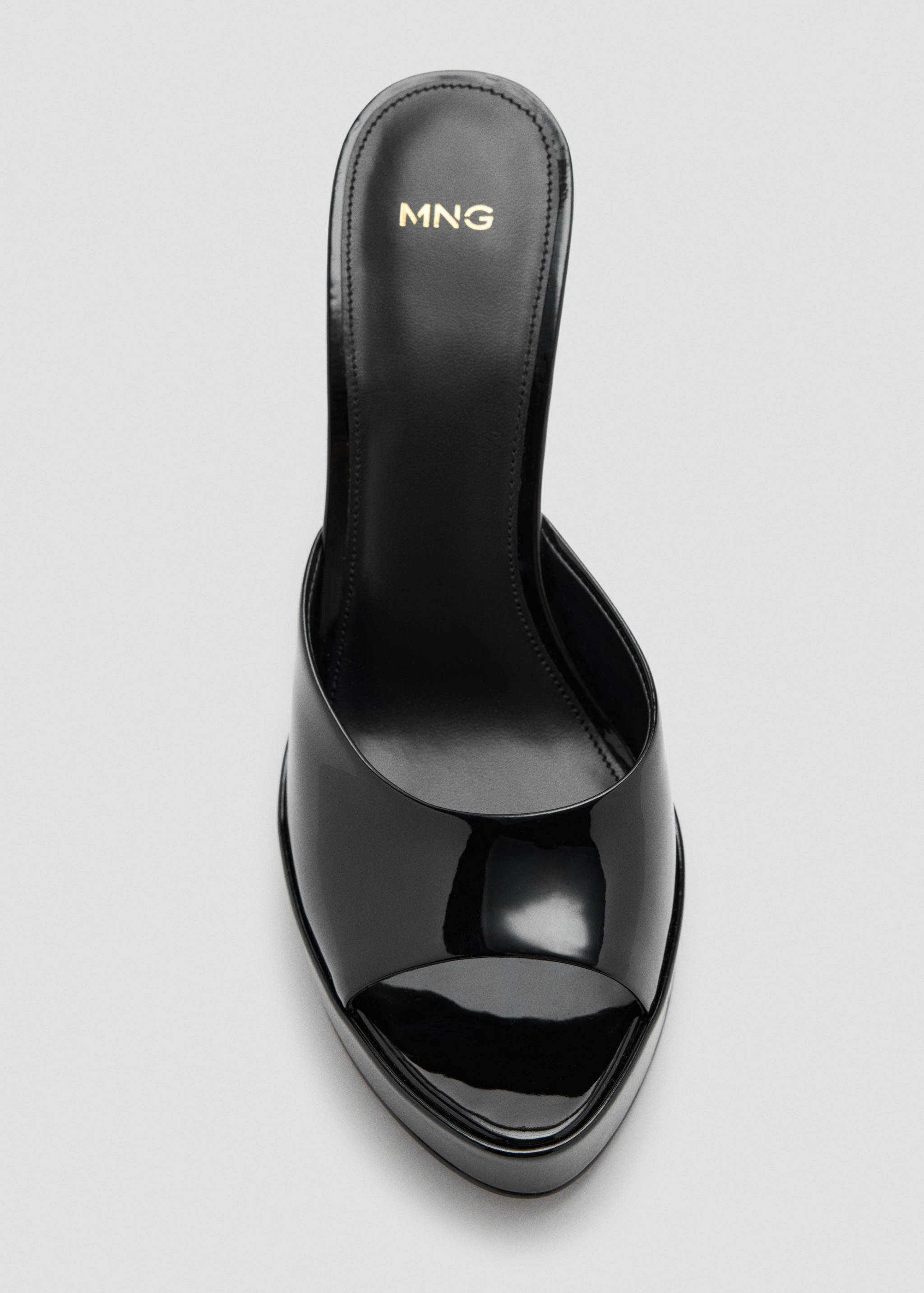 Close-up of a black patent leather heeled sandal with a platform sole.