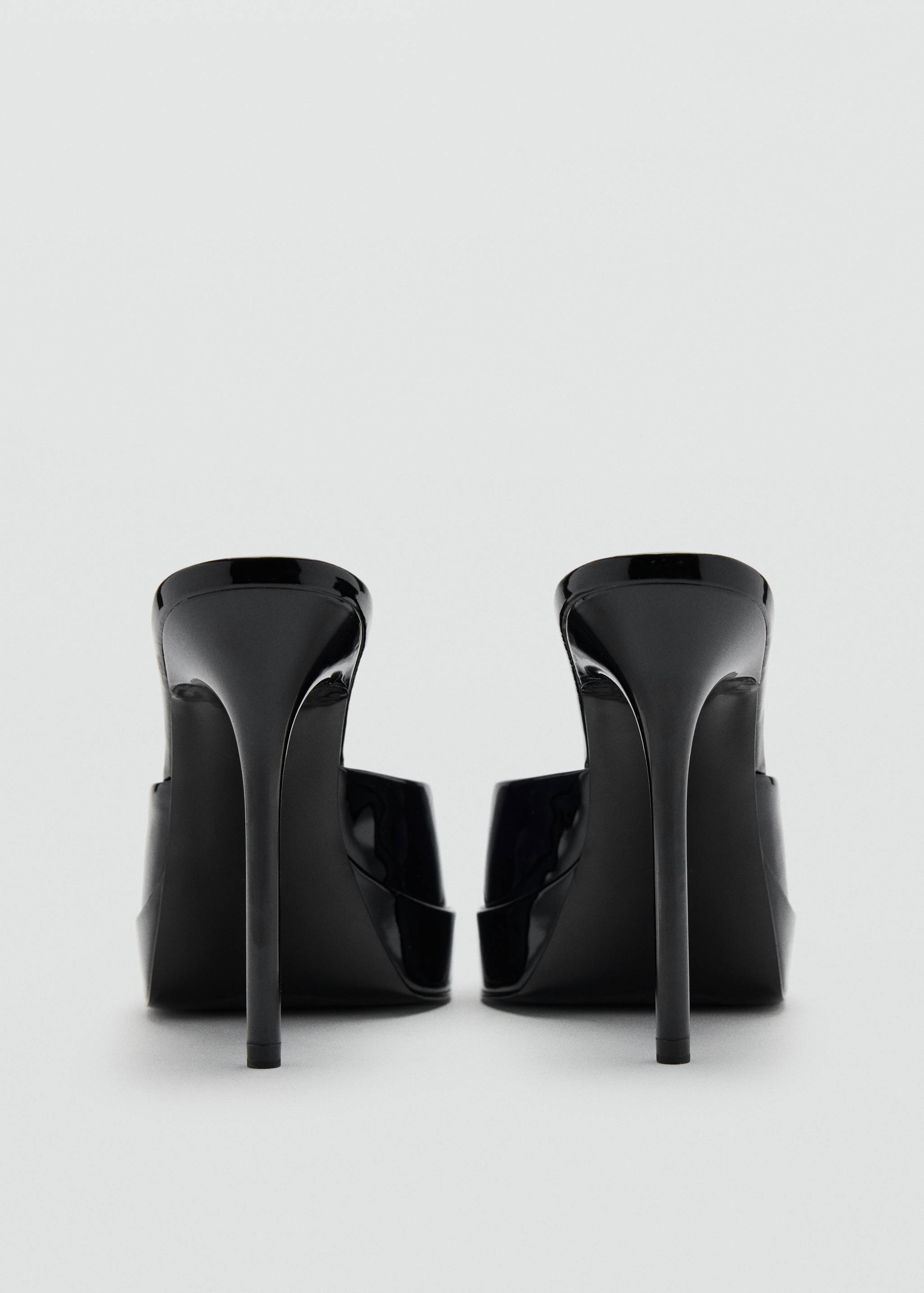 Black patent heeled sandals with high stiletto heels, viewed from the back.