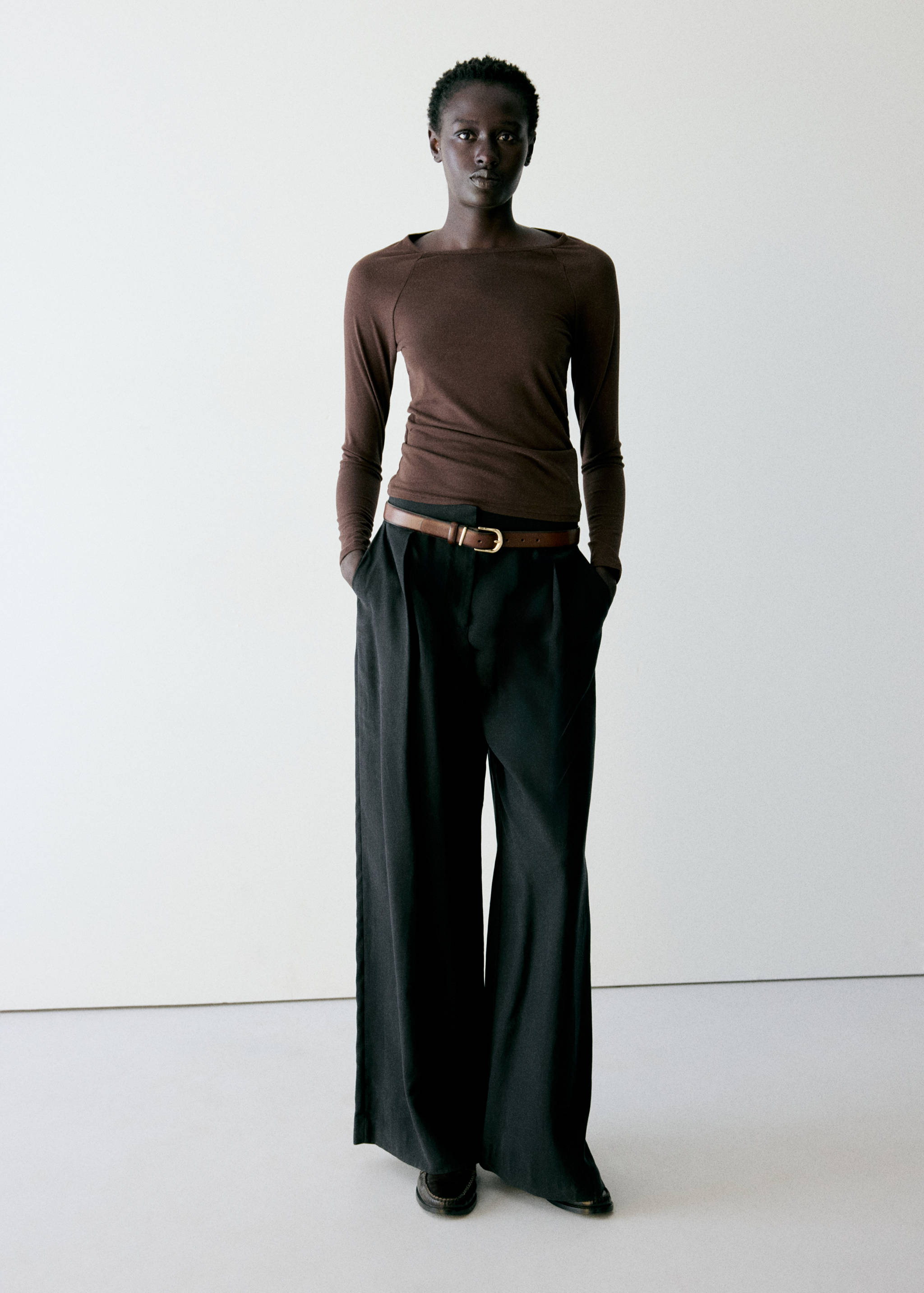 Brown long-sleeved slim-fit t-shirt worn with pleated black trousers