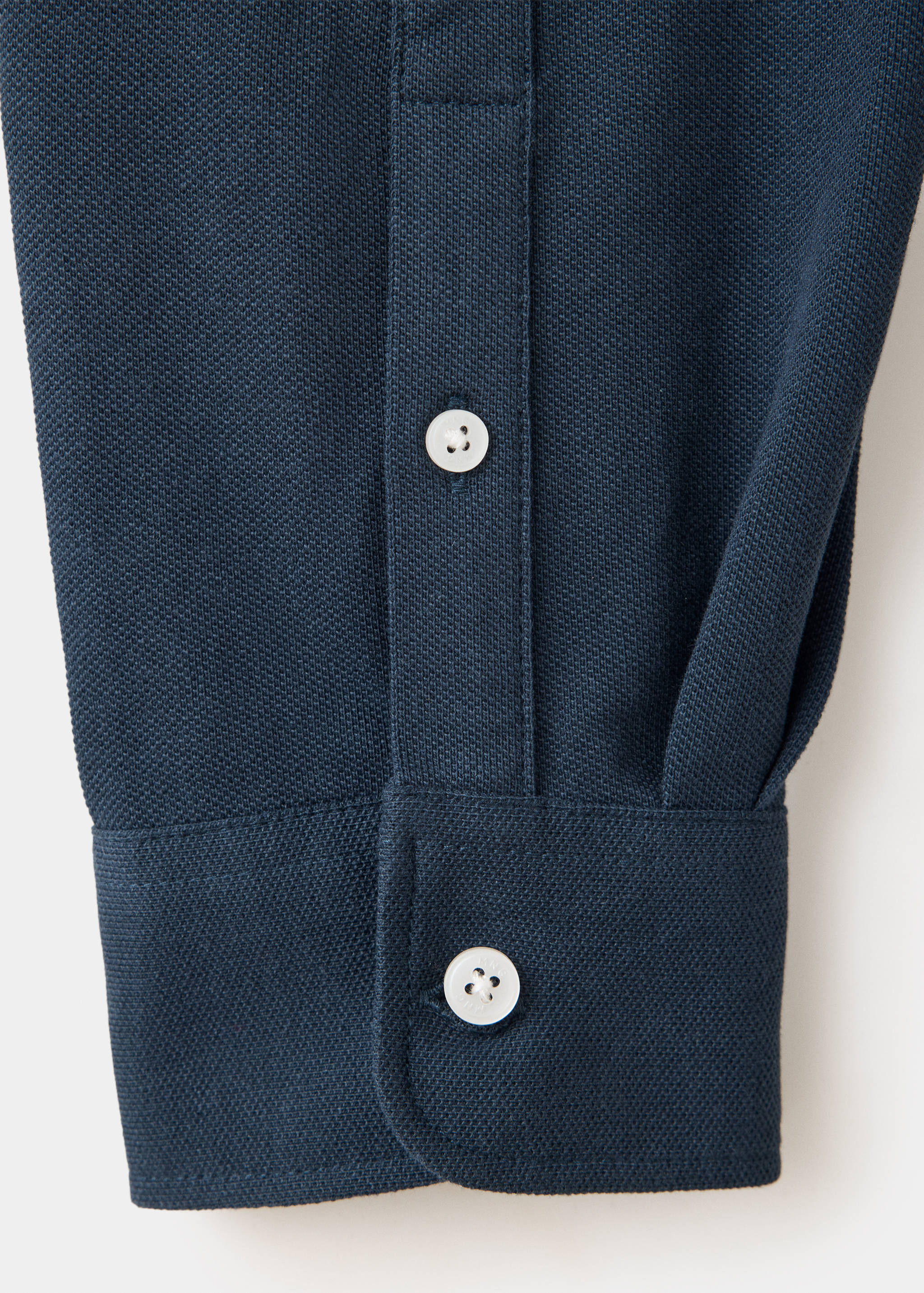 Dark navy blue polo shirt texture detail showing the buttoned cuff.