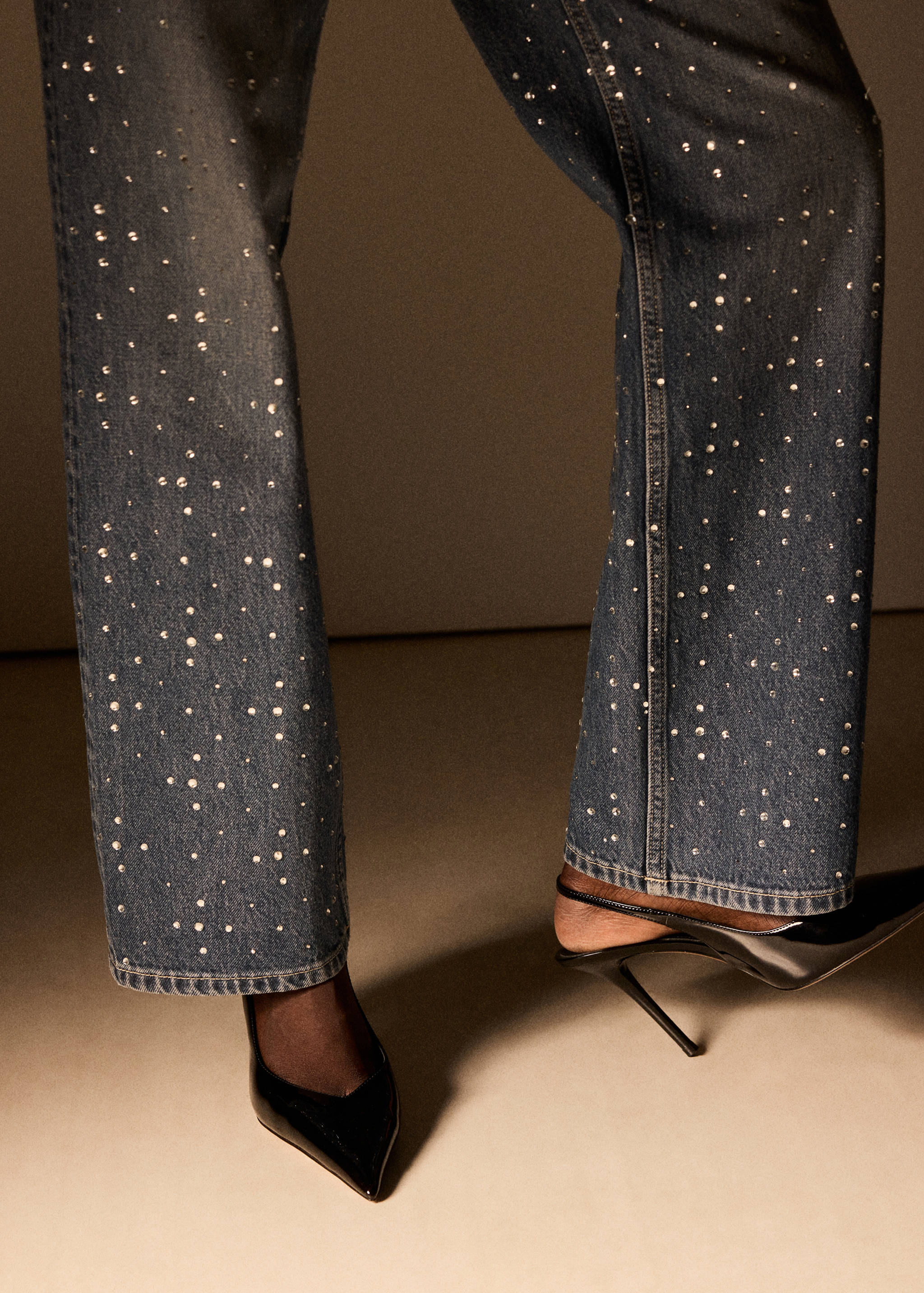 Dark blue rhinestone-embellished denim trousers worn with black heels.