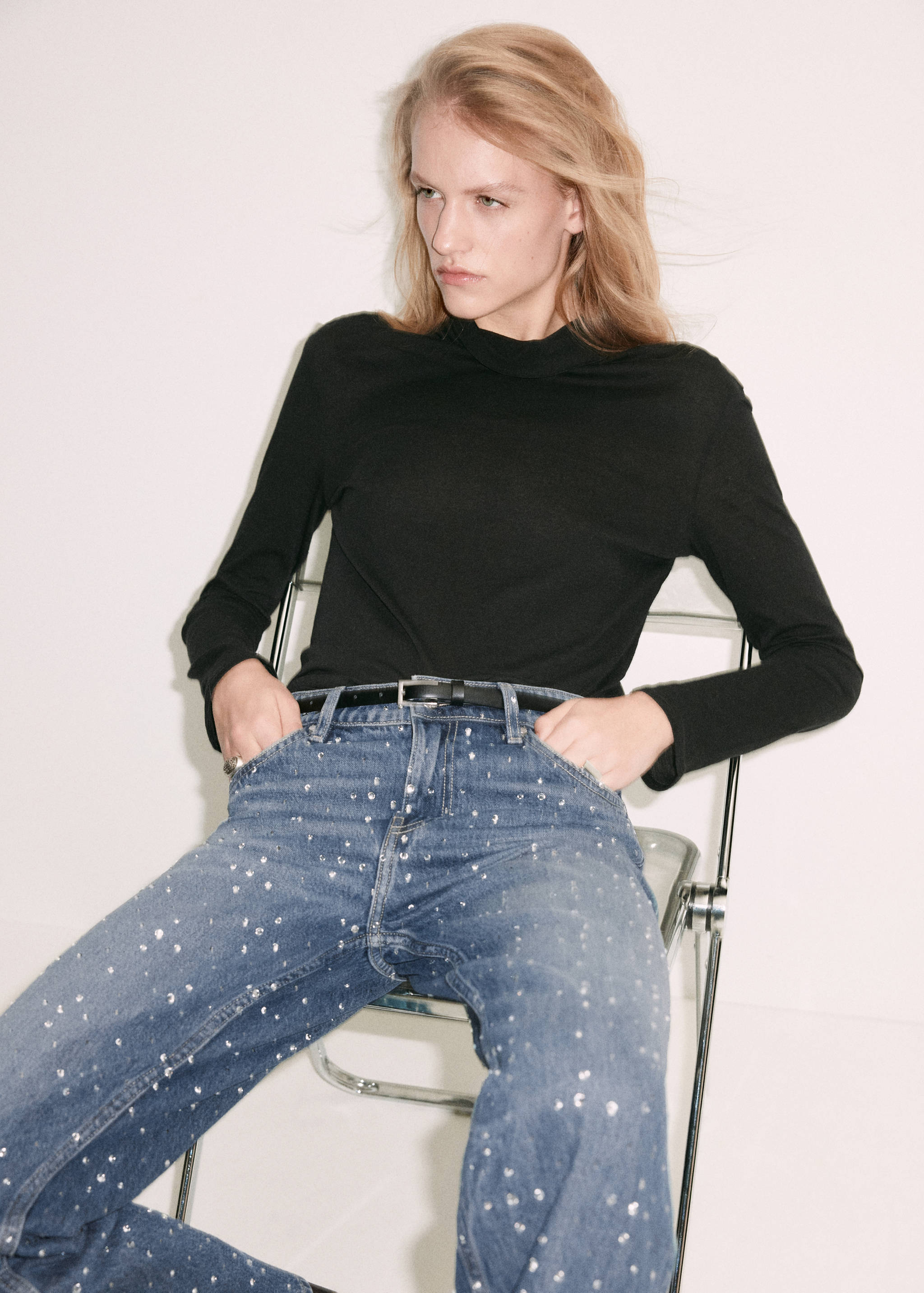 Rhinestone-embellished blue denim trousers worn with a black top.