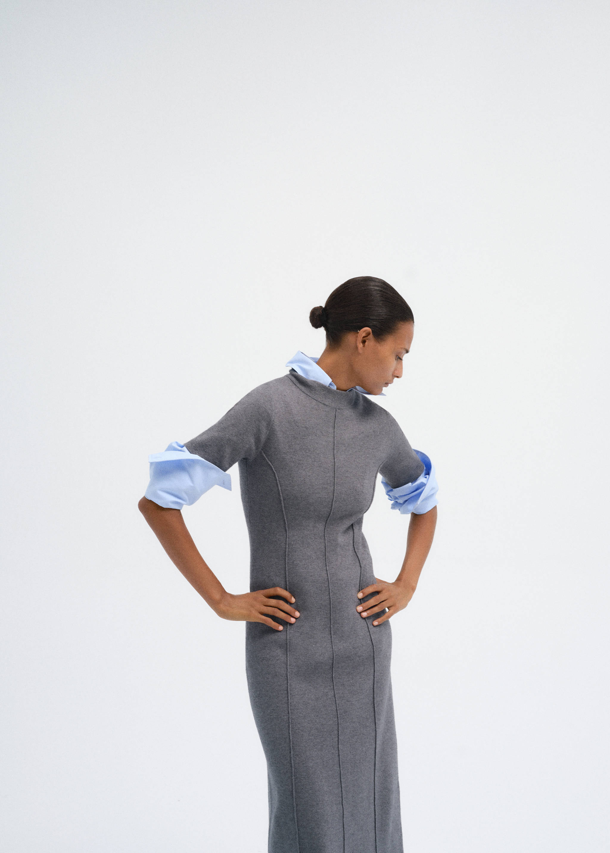 Fitted grey knit dress with short sleeves layered over a blue shirt.