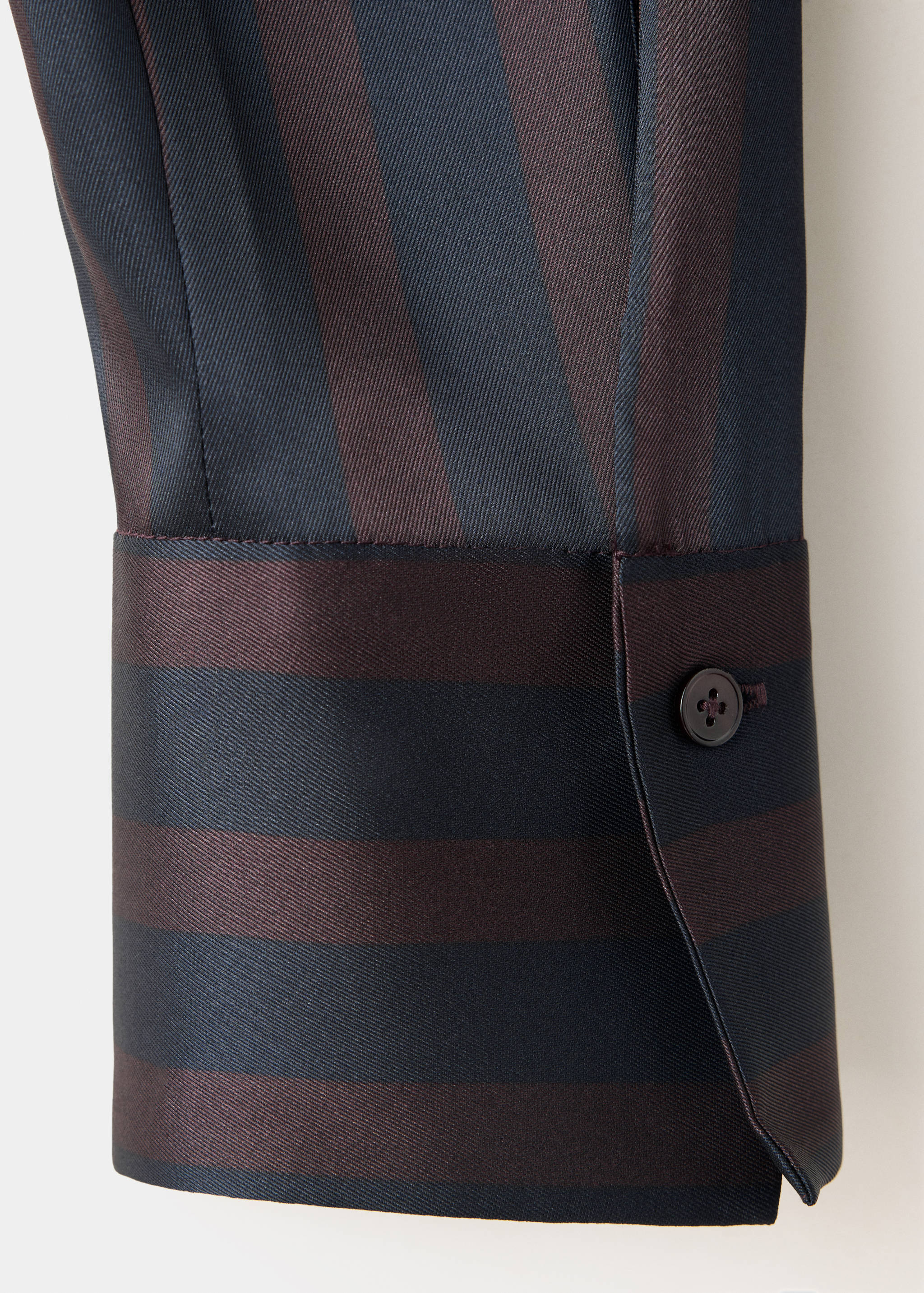 Close-up of a striped blouse cuff with dark blue and brown patterns.