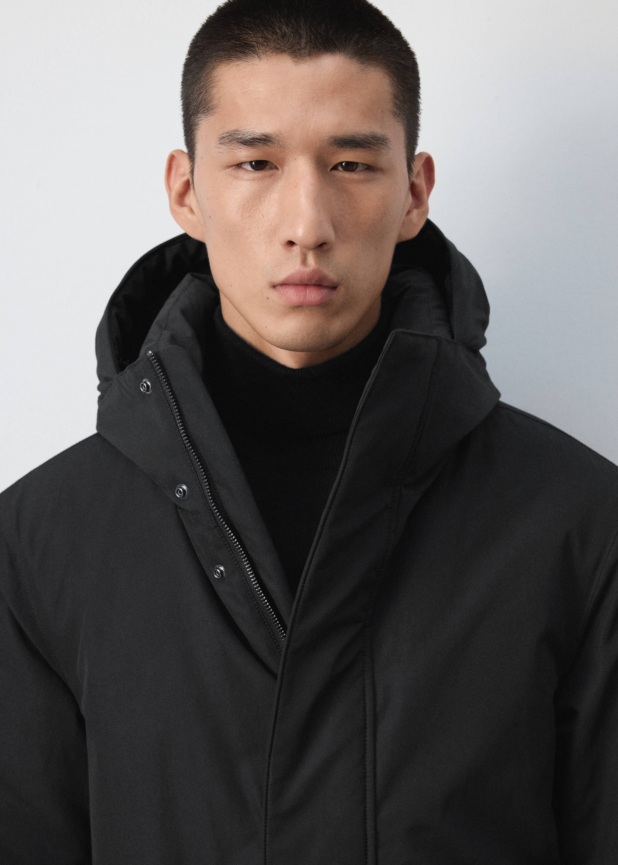 Black hooded parka with zip and snap-button fastening.