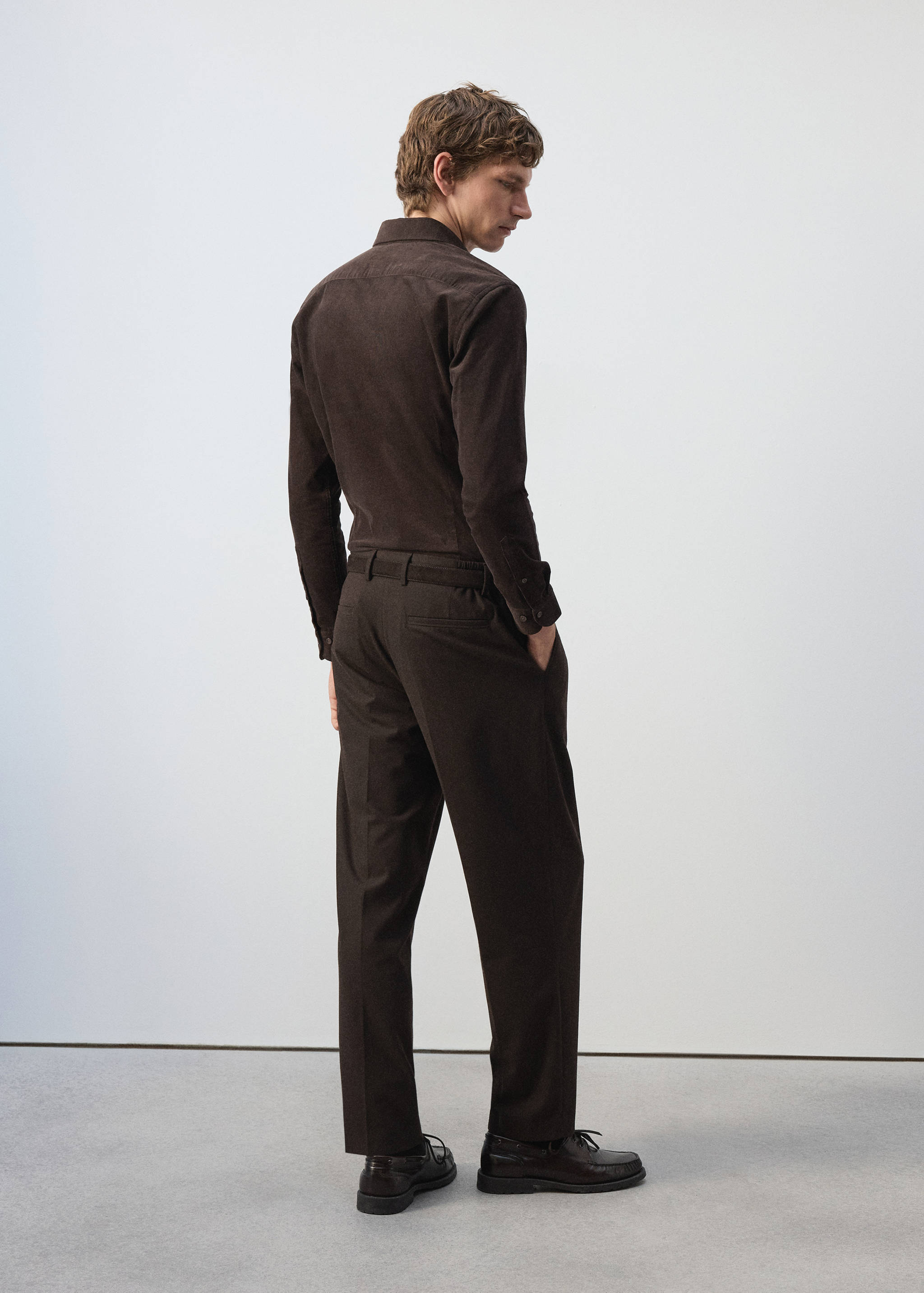 Back view of a dark brown corduroy shirt worn by a male model.