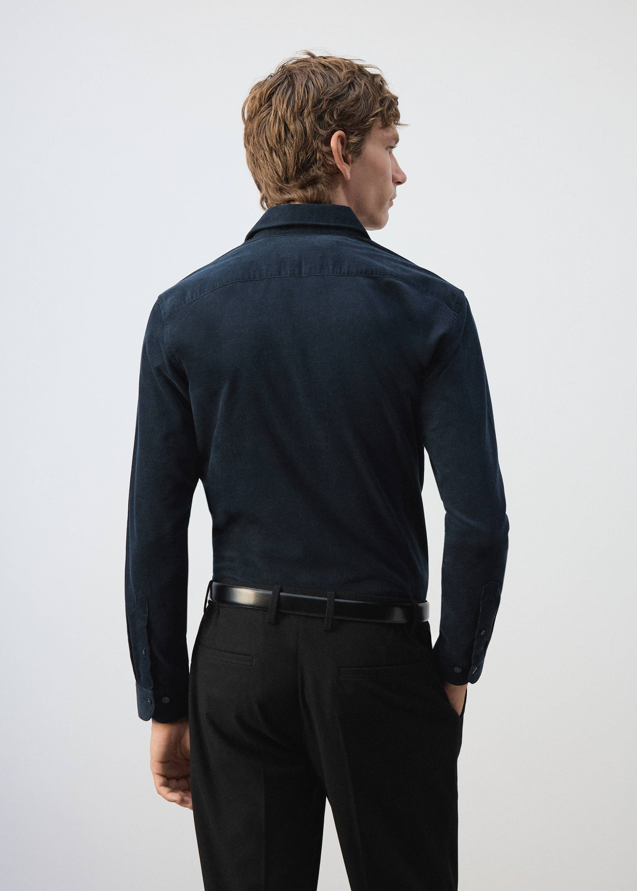 Dark blue long-sleeved shirt viewed from the back, worn with black trousers.