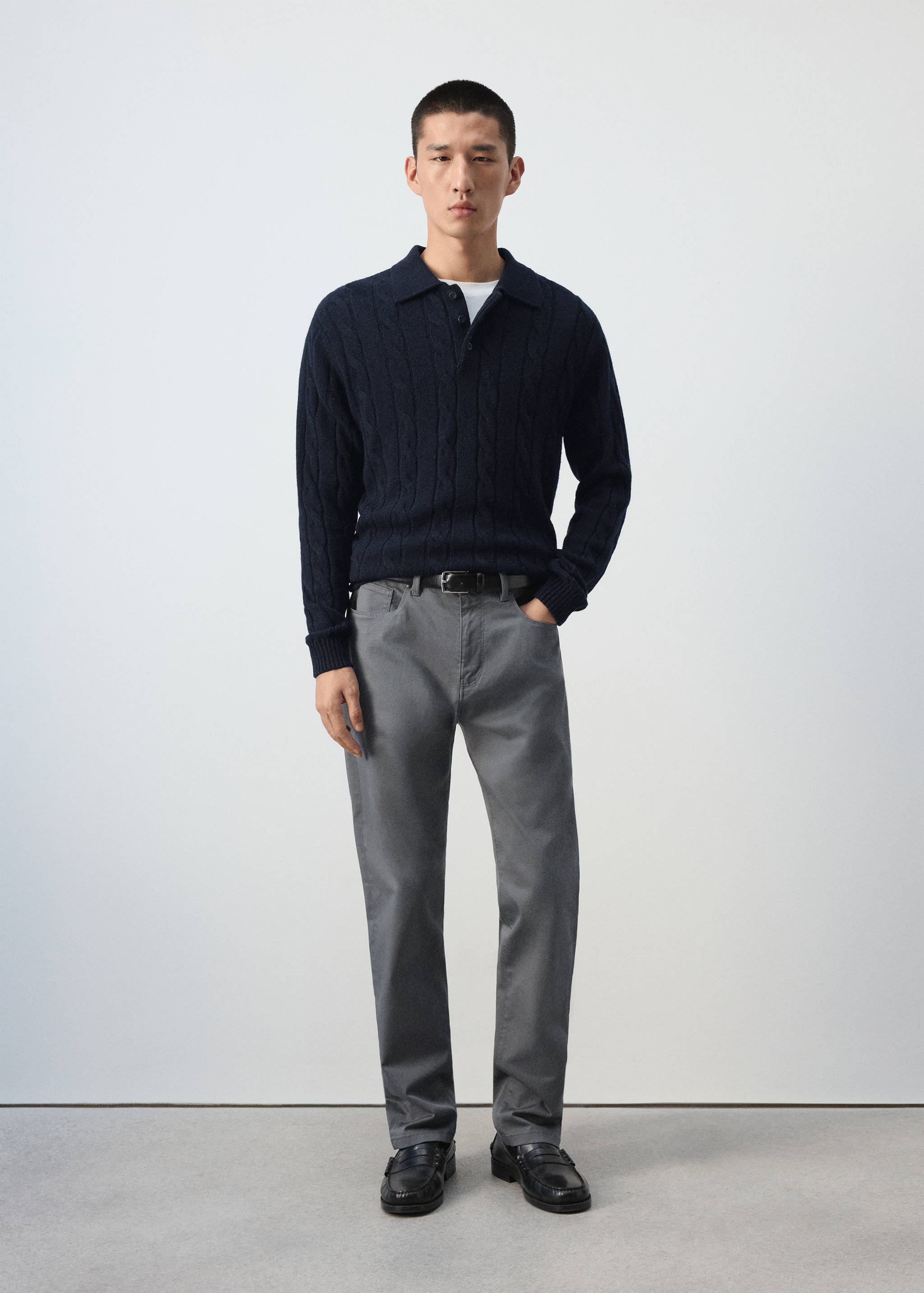 Navy blue cable-knit polo shirt worn with grey trousers
