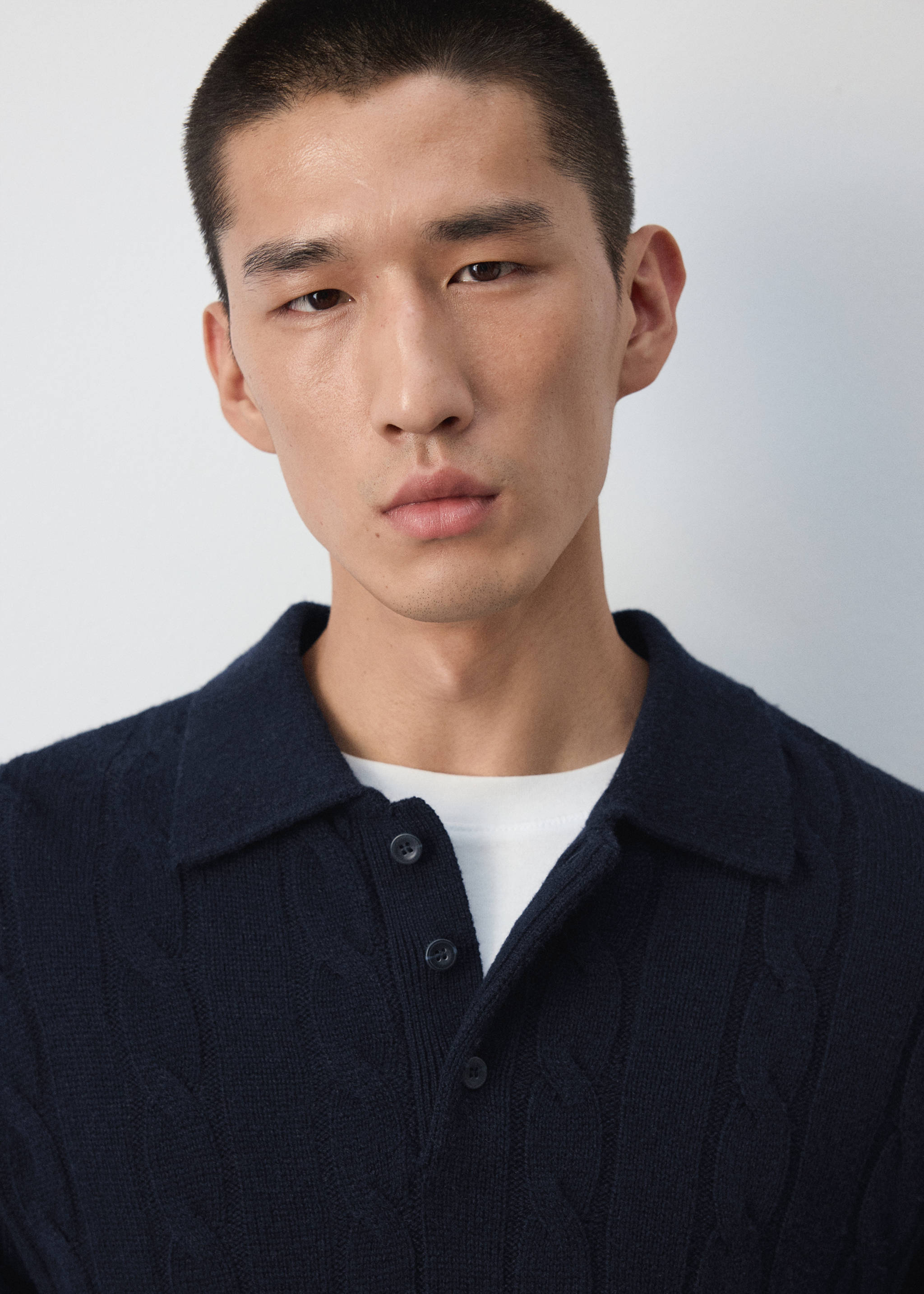 Navy blue cable-knit polo shirt with a classic collar and button placket.