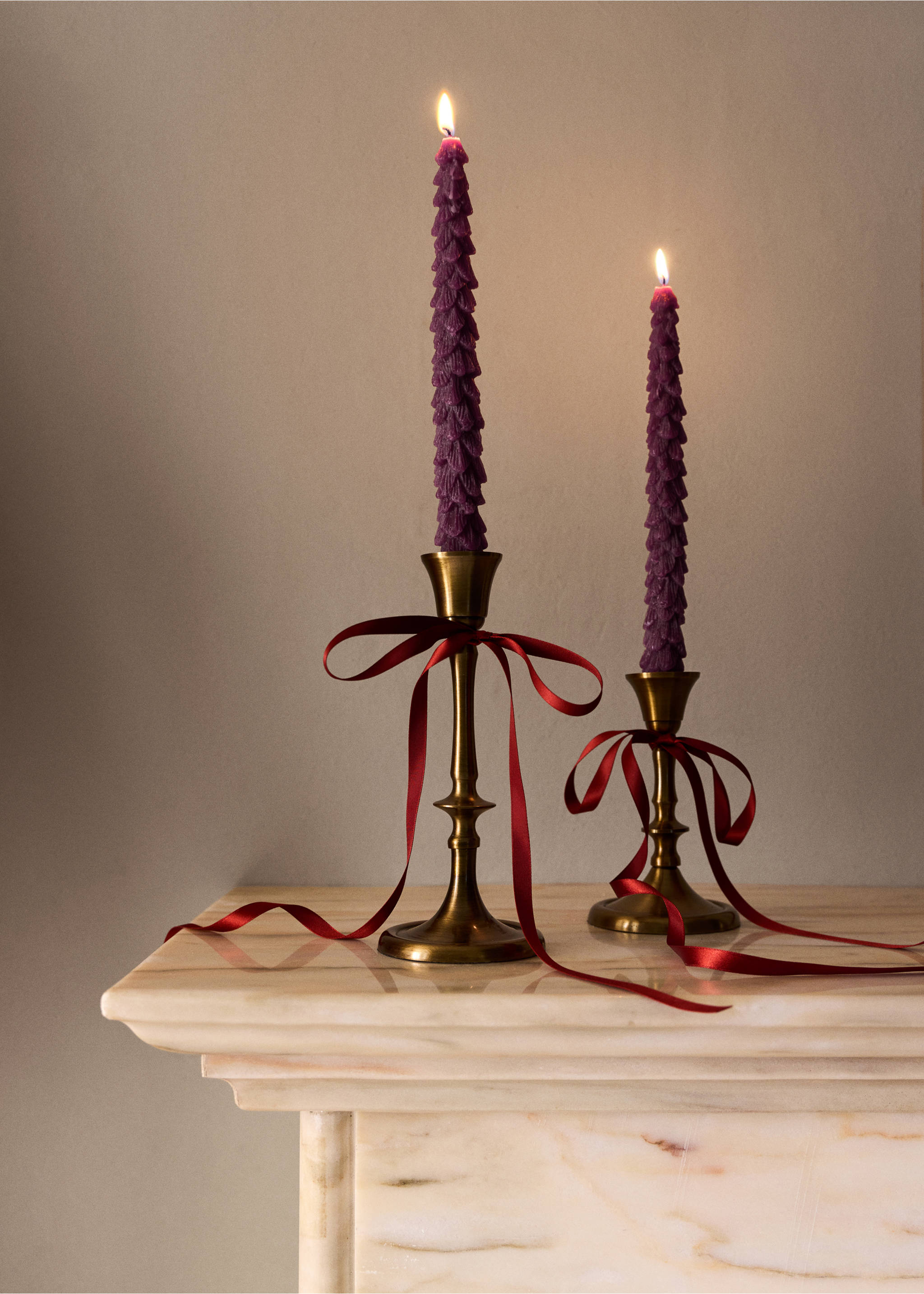 Two lit textured purple candles in brass holders with red ribbons., Maroon. Ref: 37097889-00.