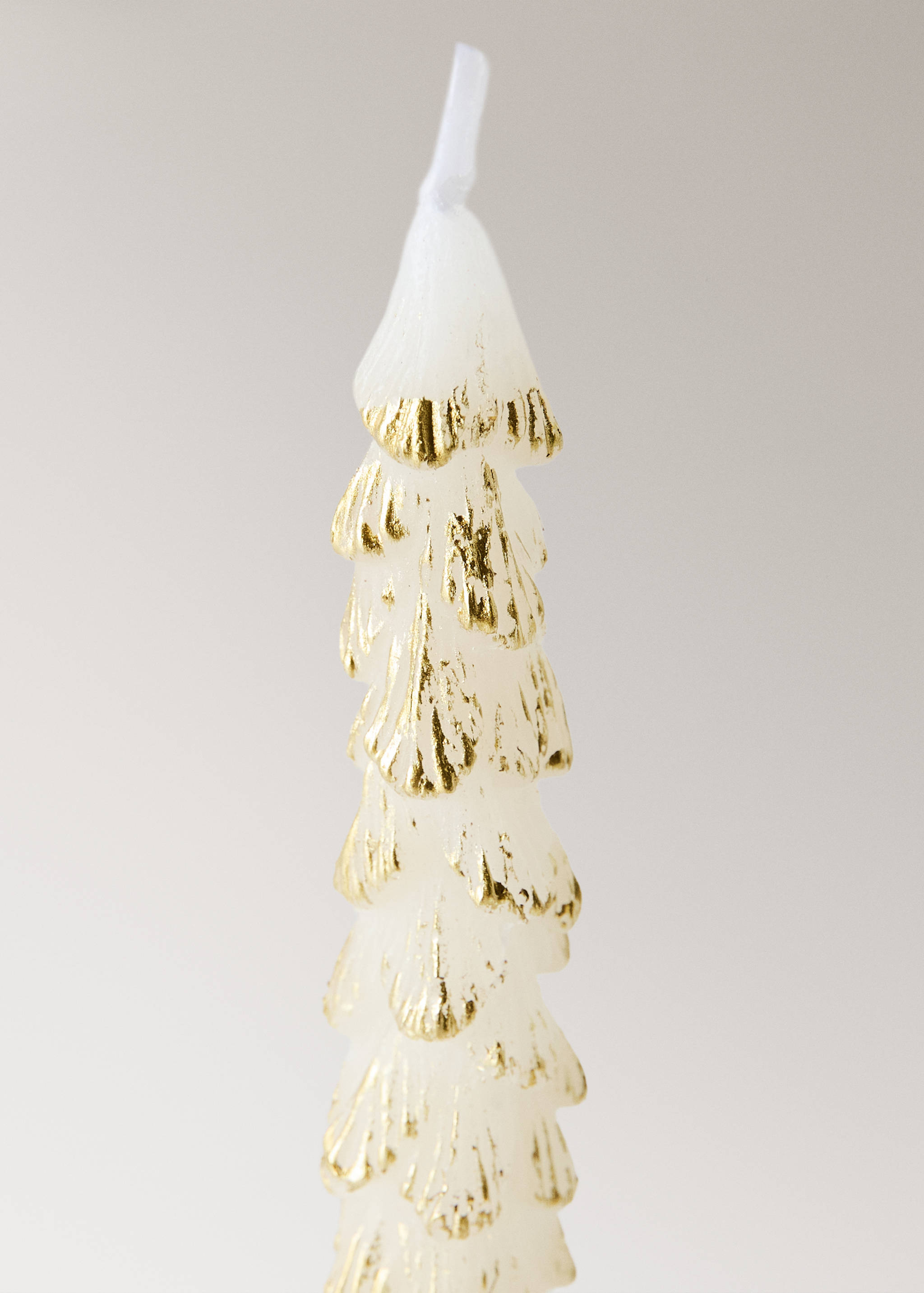 White Christmas tree-shaped candle with gold highlights.