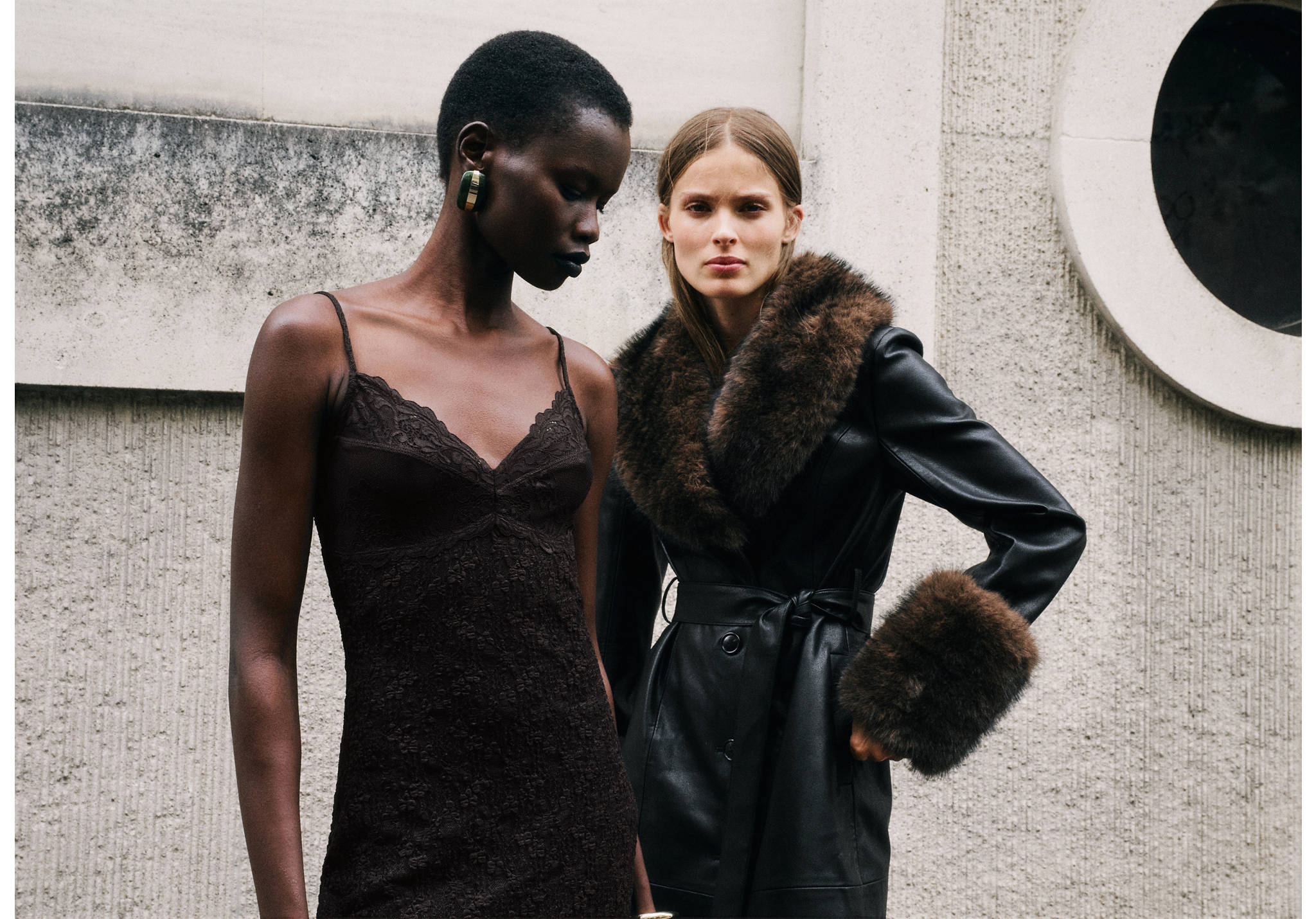 Black faux-leather coat with brown faux-fur collar and cuffs, worn by a model.