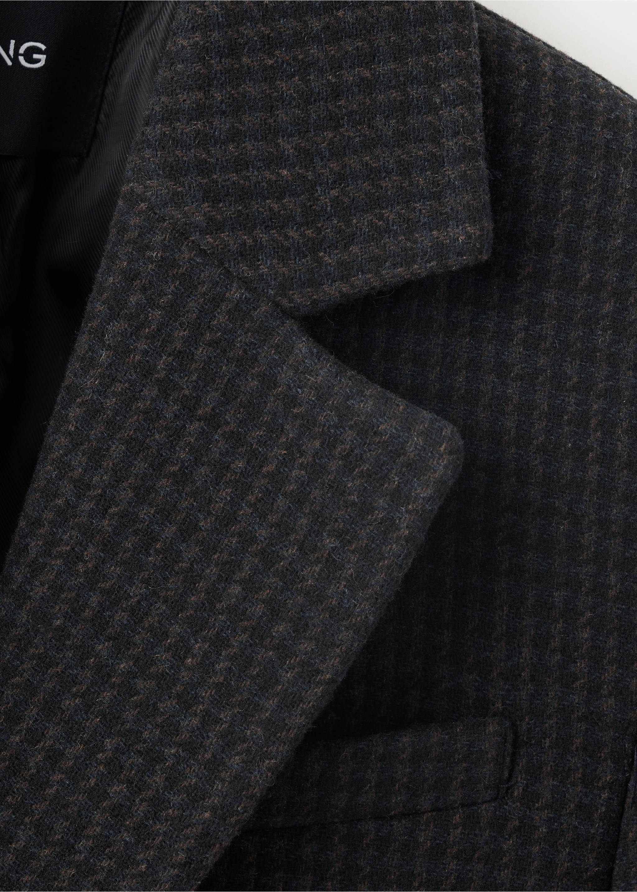 Close-up of the textured fabric and lapel of a dark grey and brown houndstooth blazer., Blue. Ref: 37097912-00.