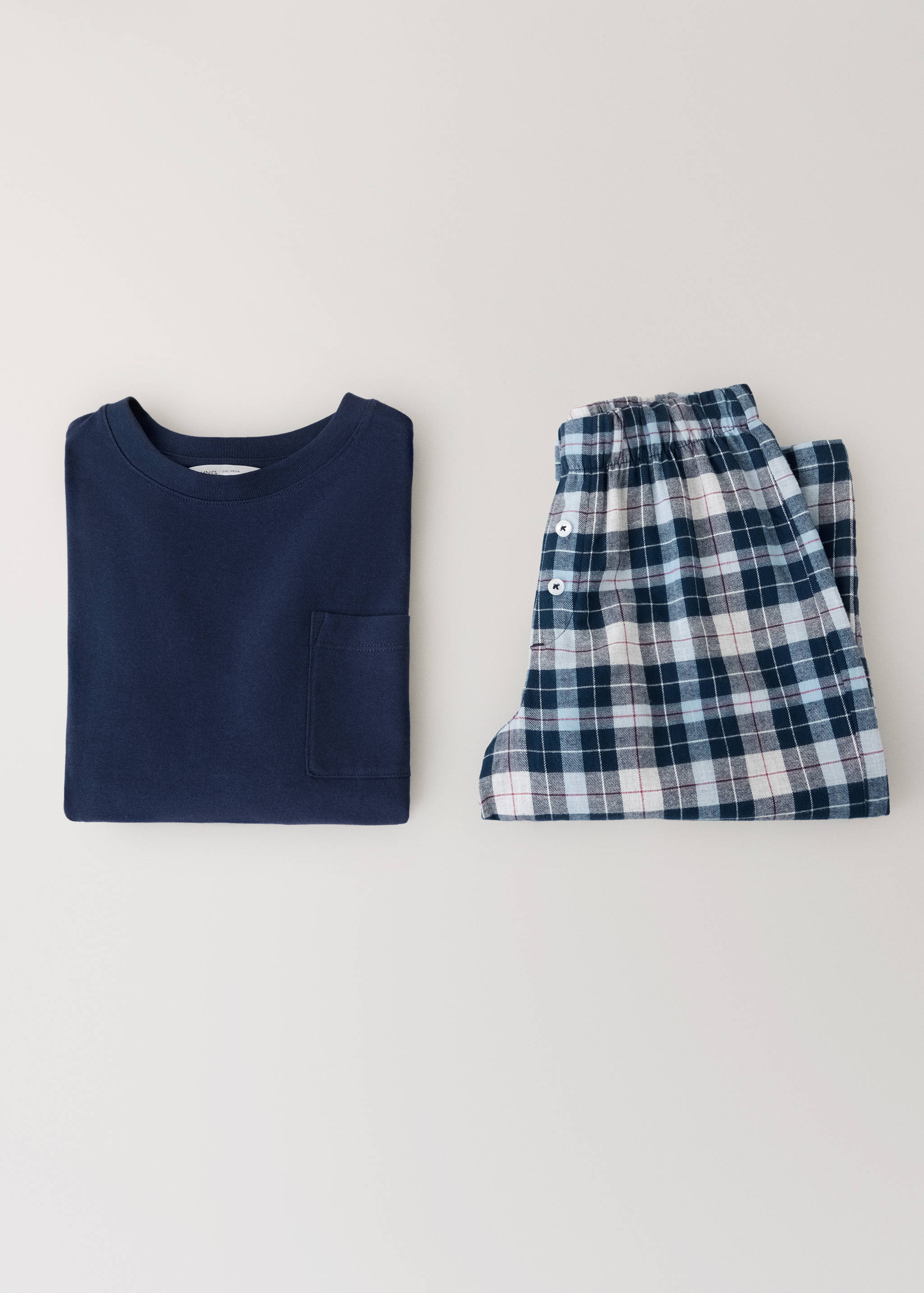 Navy blue pyjama top with pocket and blue plaid trousers.