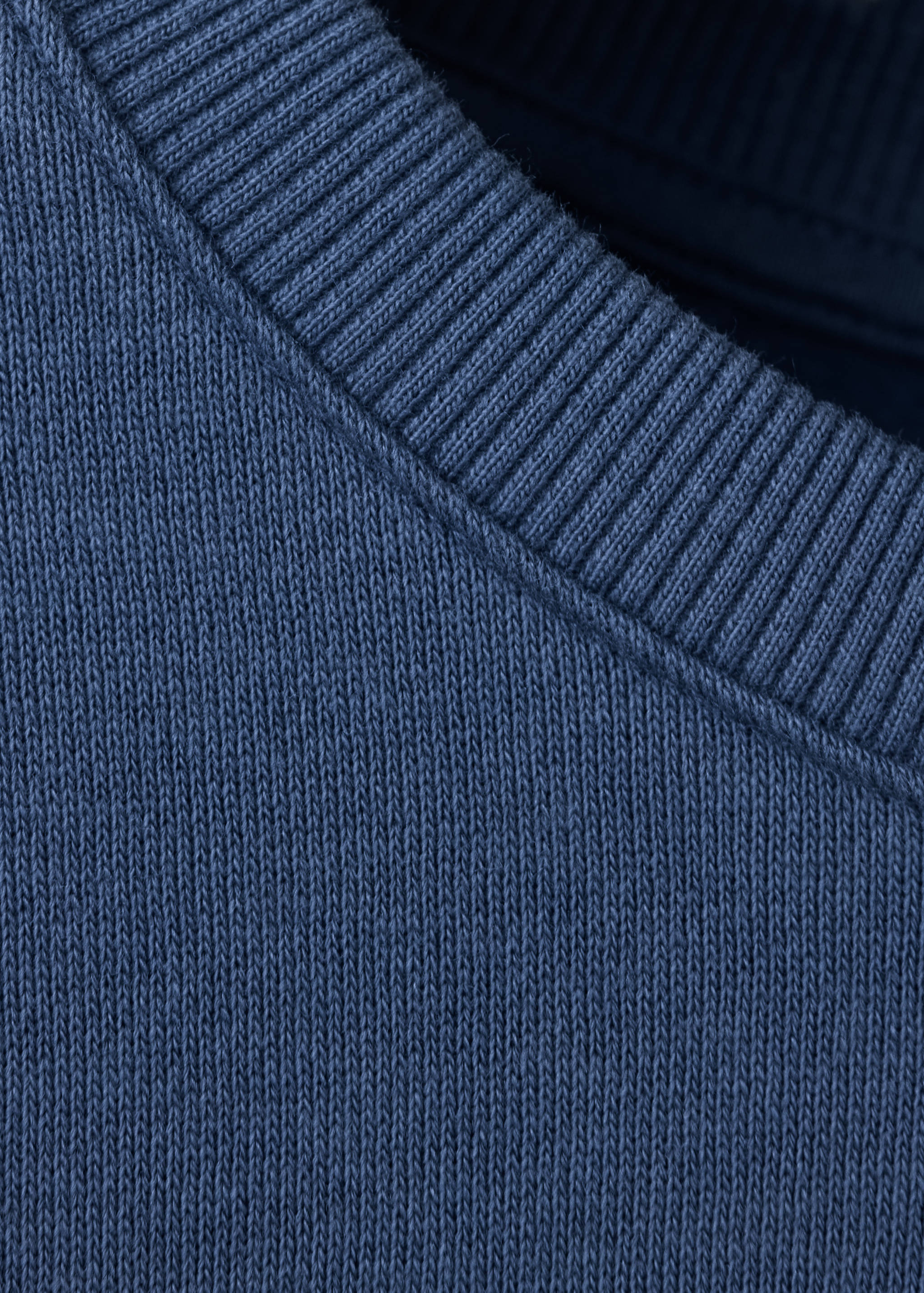 Primer plano de una sudadera azul oscuro que detalla el cuello redondo de canalé.
