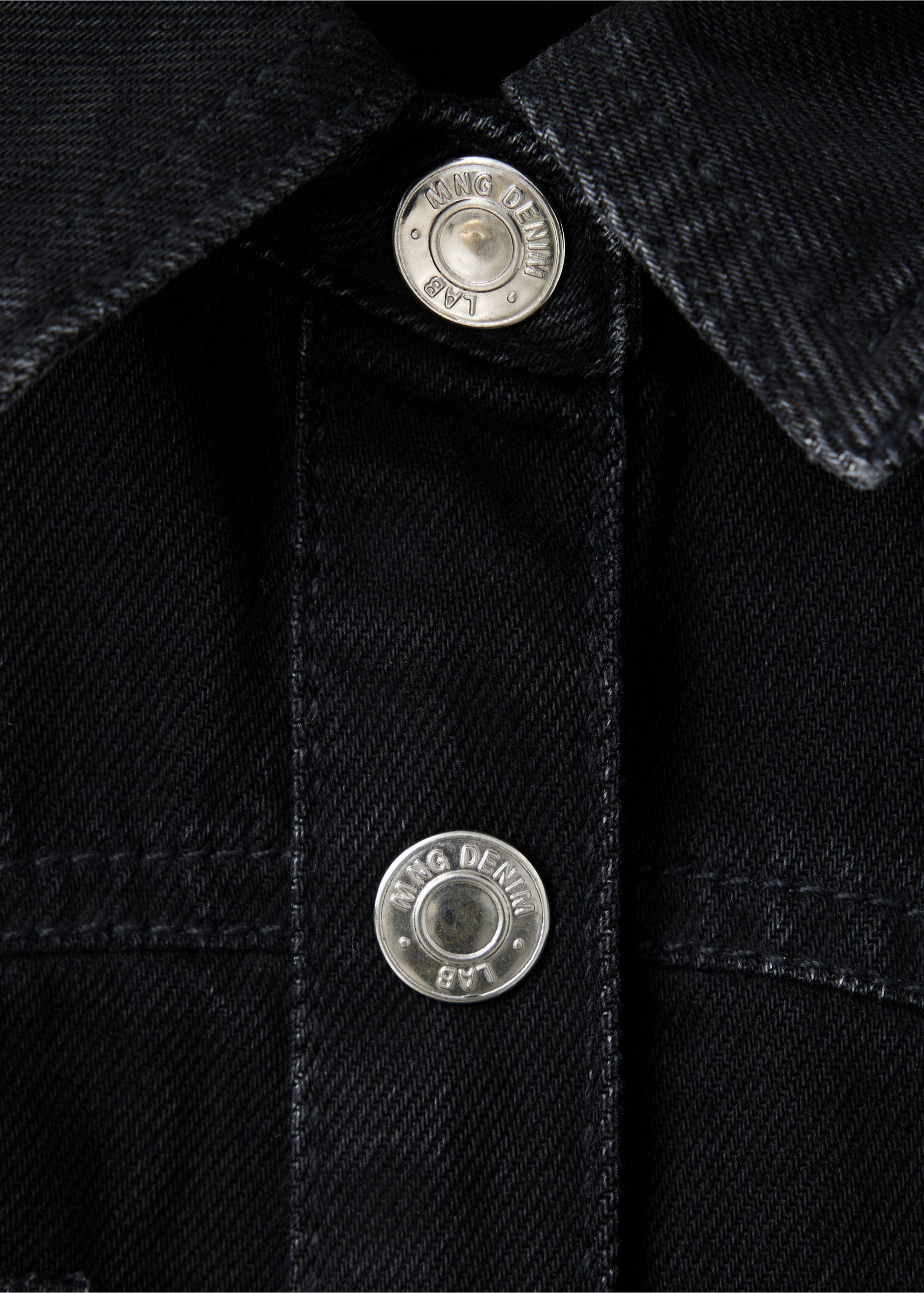 Close-up of a black denim dress detail showing metallic logo buttons., Black denim. Ref: 37097932-00.