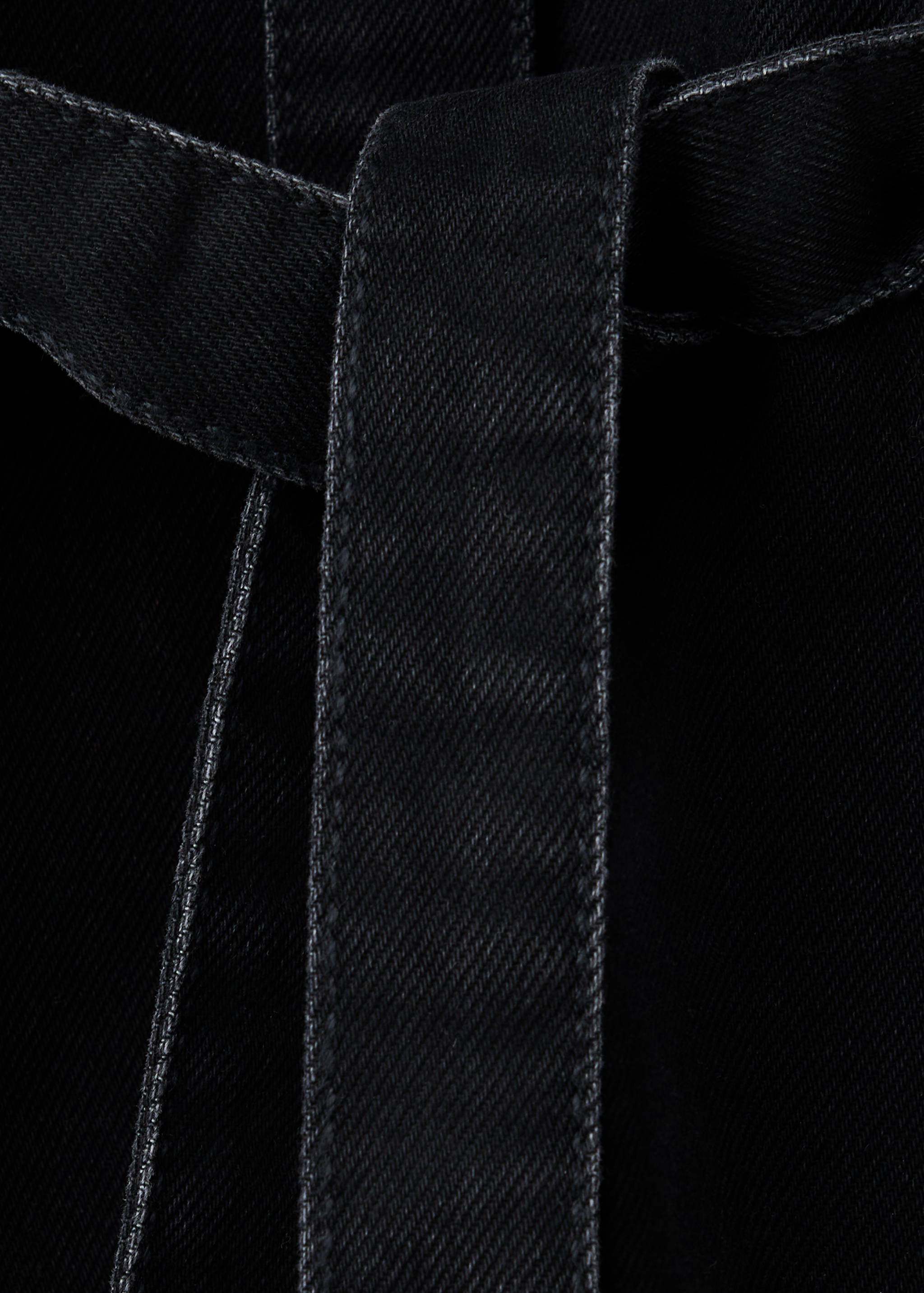 Close-up of a black denim dress fabric texture and belt detail.
