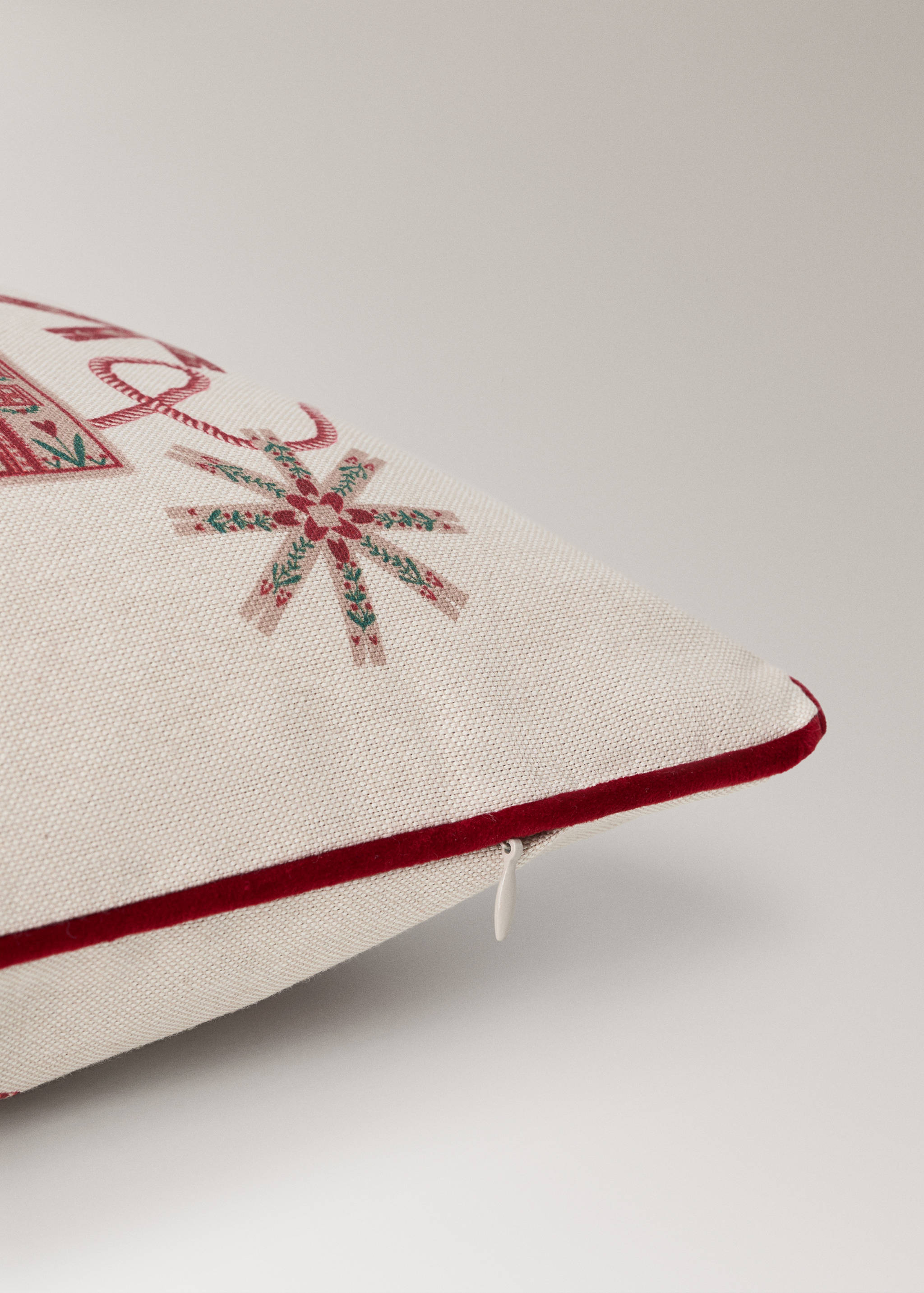 Cushion cover detail with festive print and red piping.