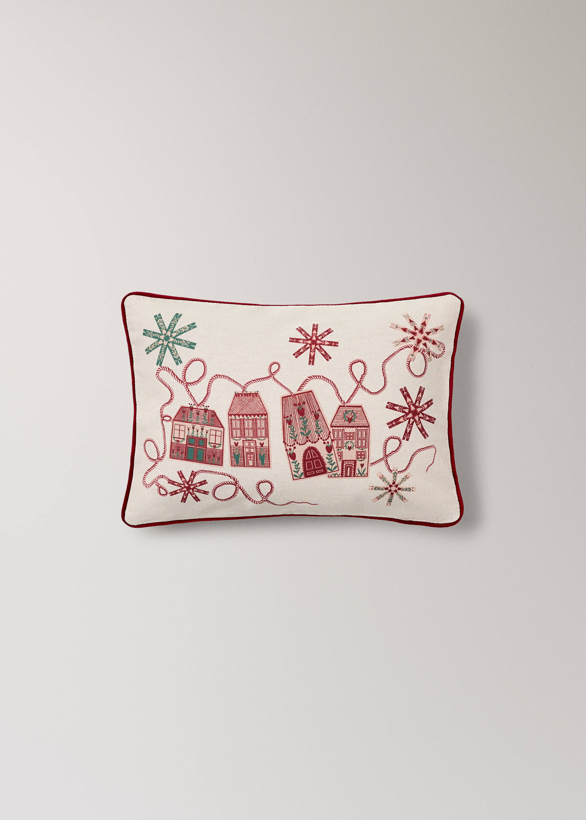 Off-white cushion cover with red piping and embroidered festive houses.