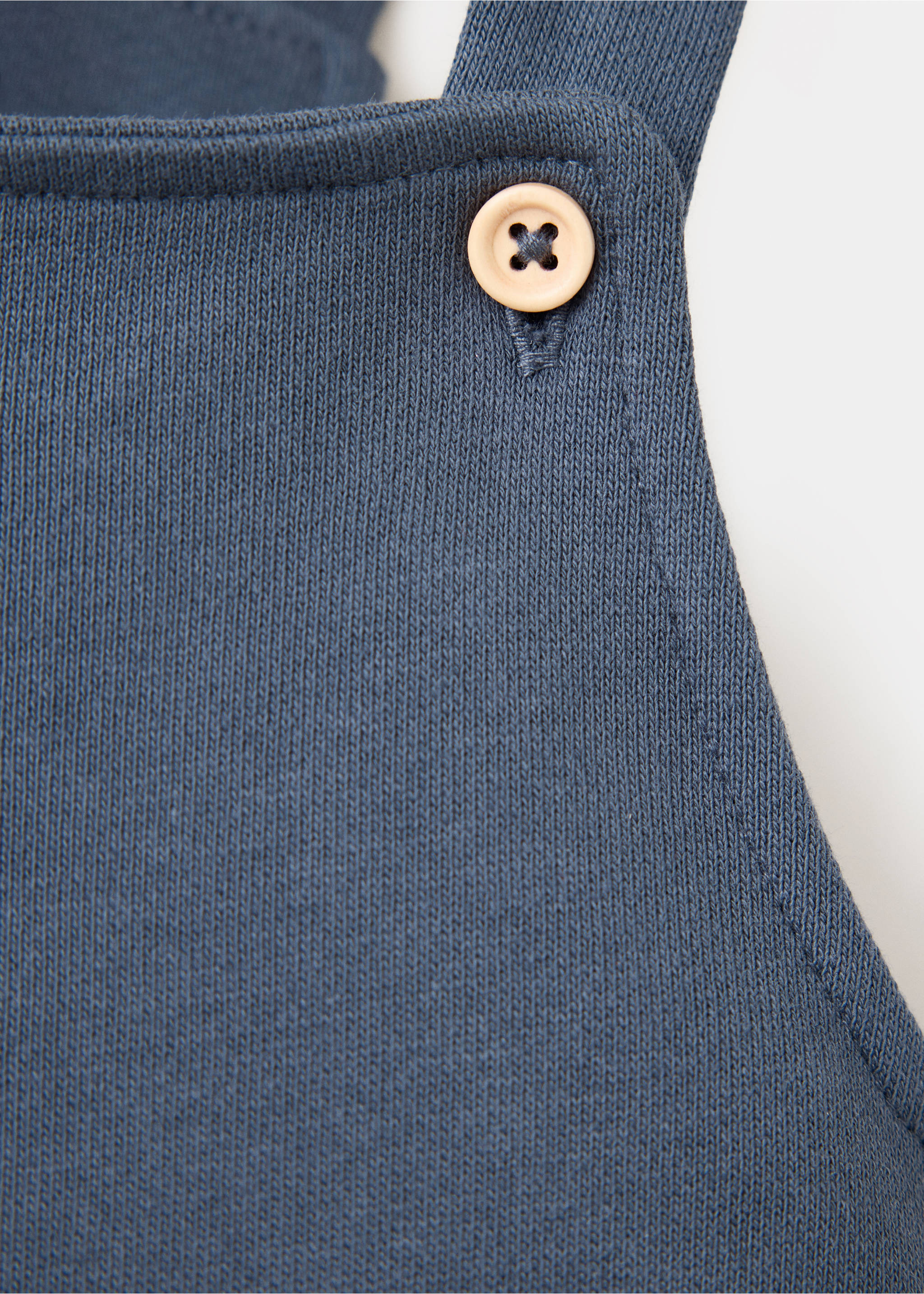 Close-up of blue knitted dungarees strap with wooden button detail., Navy. Ref: 37097936-00.