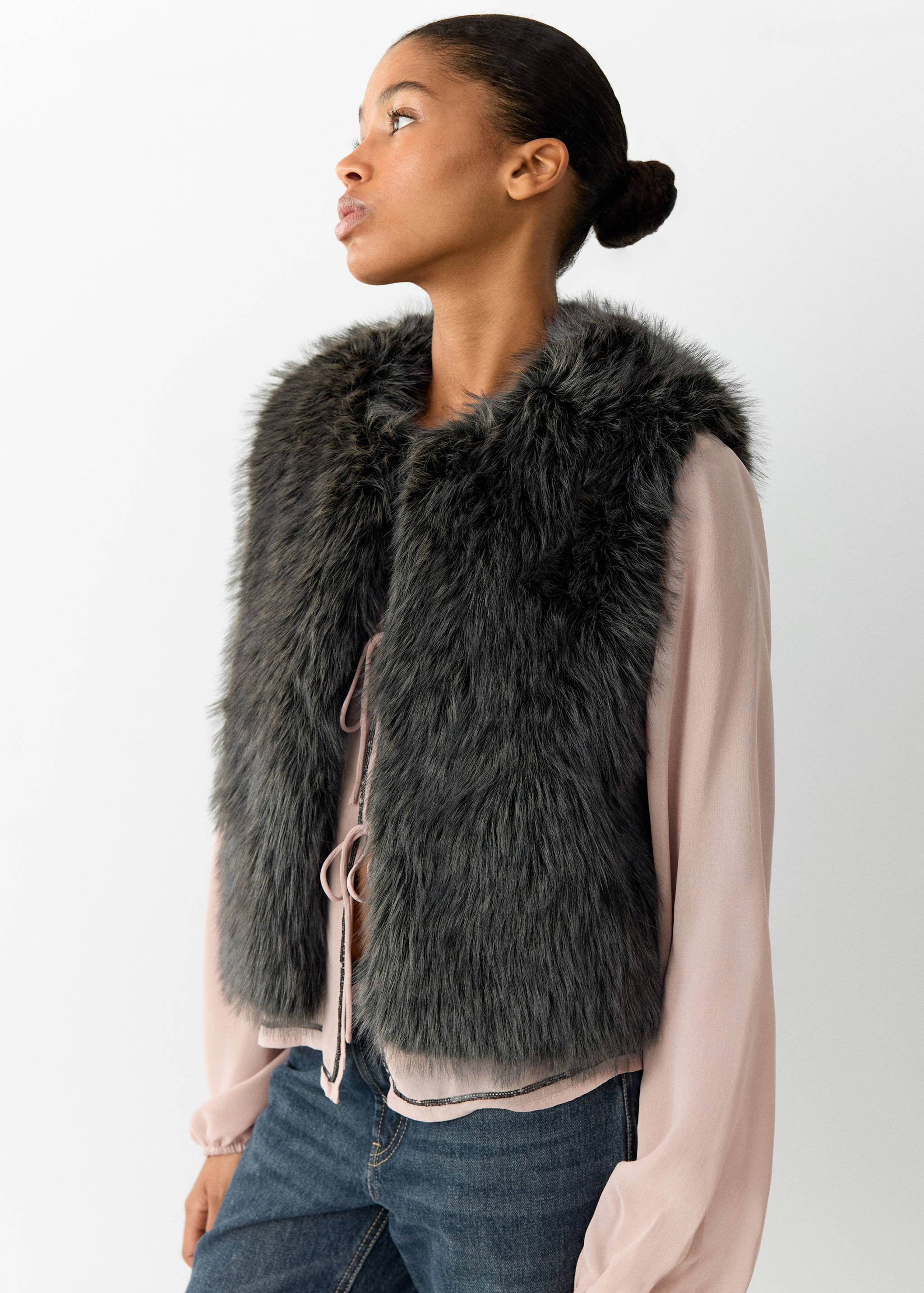 Dark grey faux-fur vest worn over a pink blouse.