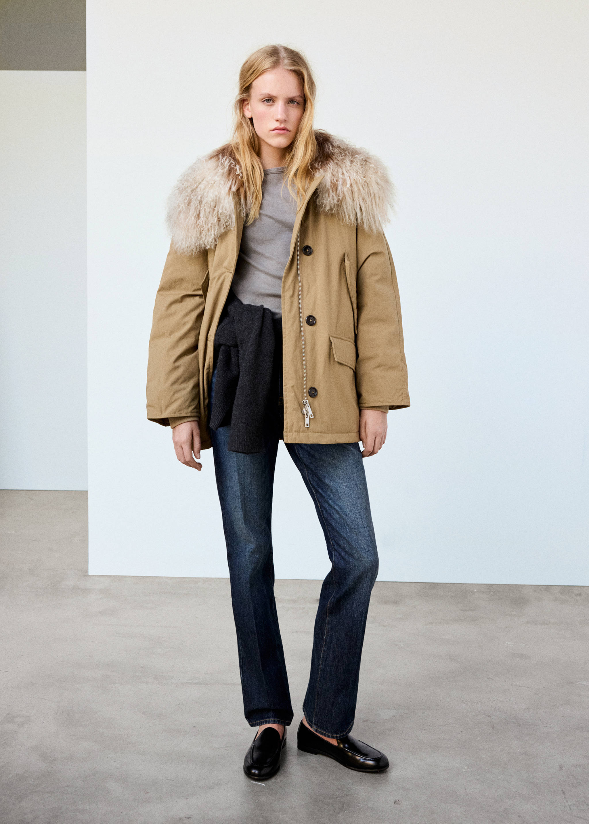 Camel parka with a cream faux-fur collar, worn with blue jeans and black boots.