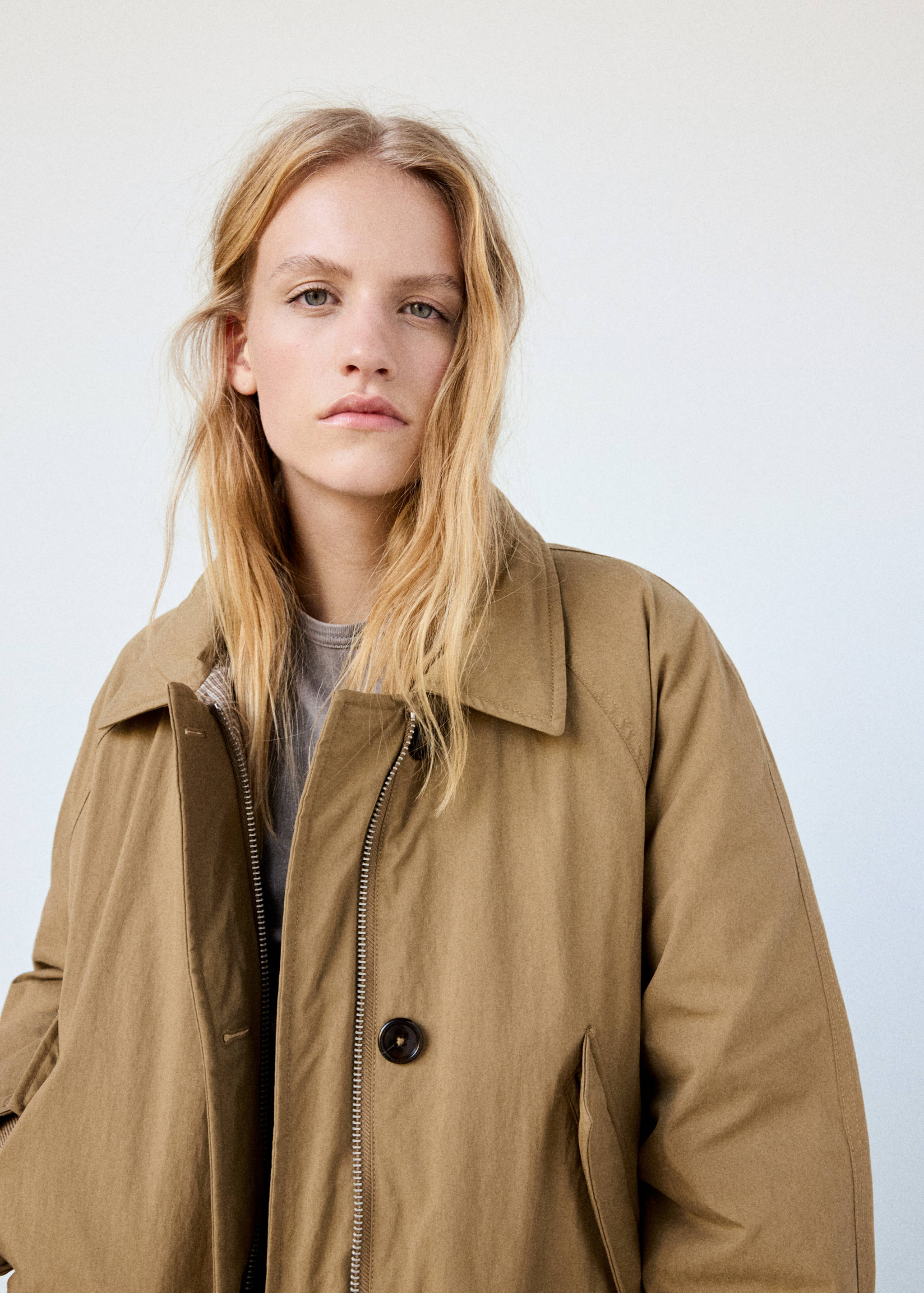 Close-up of a model wearing a tan parka with a pointed collar.