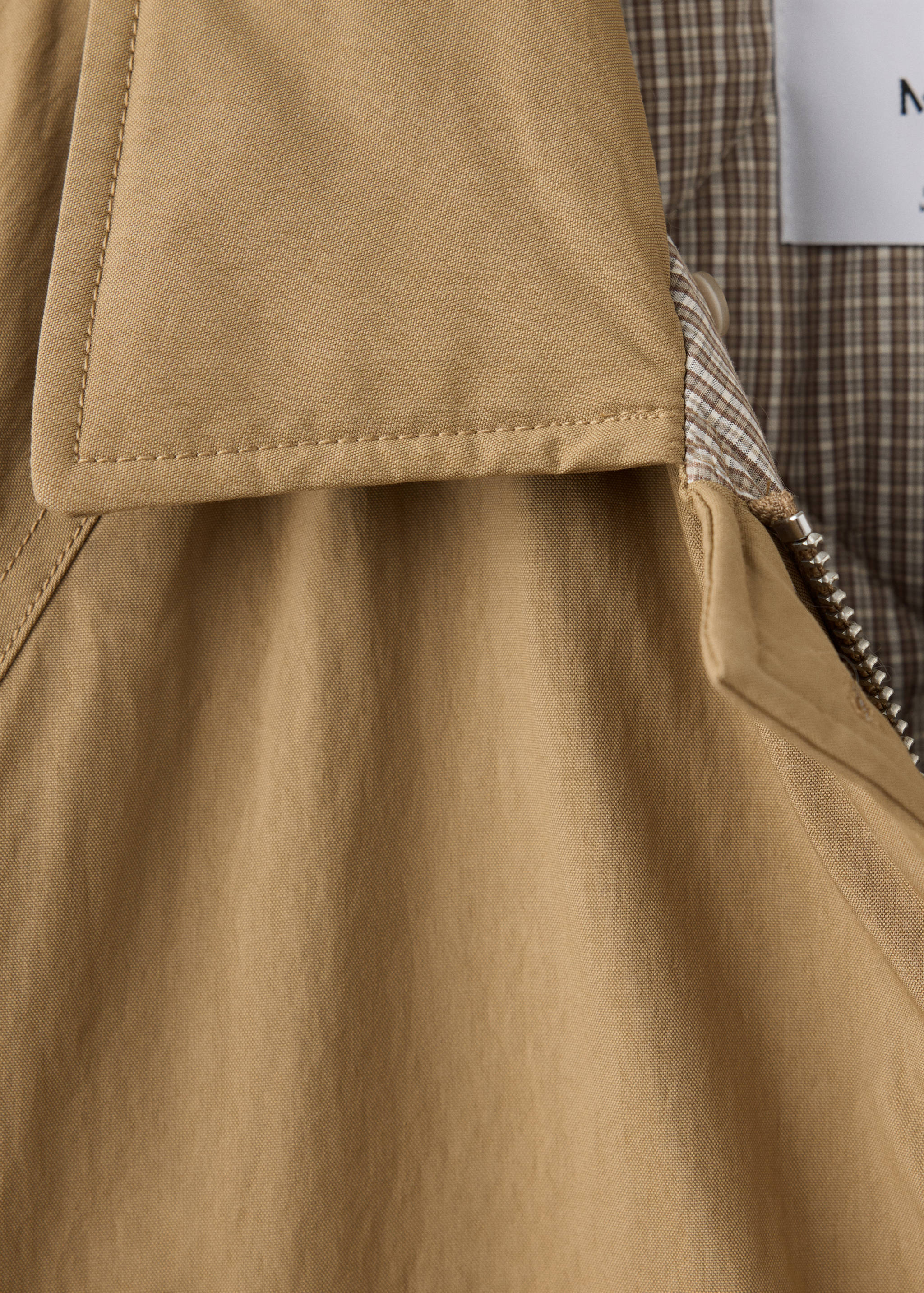 Camel parka collar and zip detail with checked lining.
