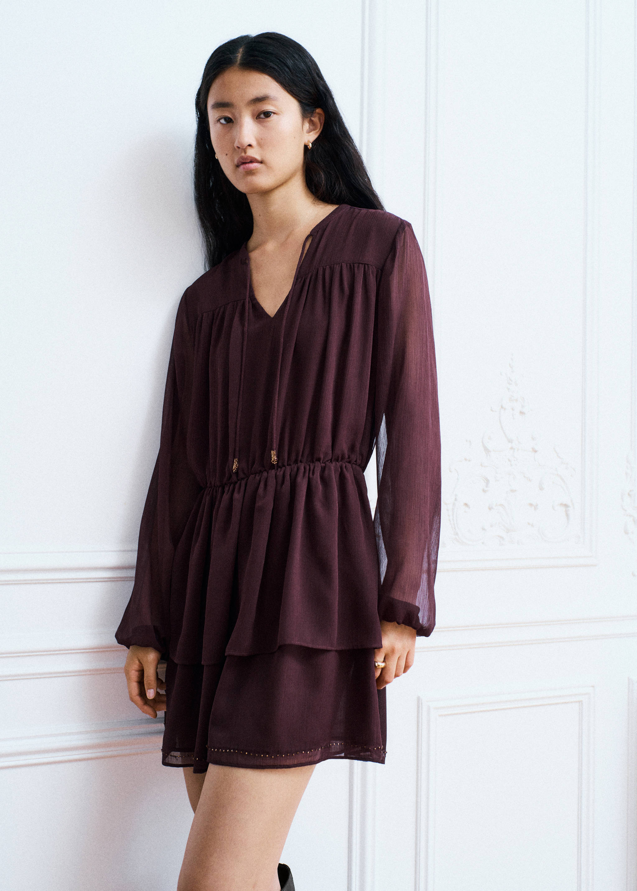 Plum long-sleeve V-neck mini dress with gathered tiers and tie detail.