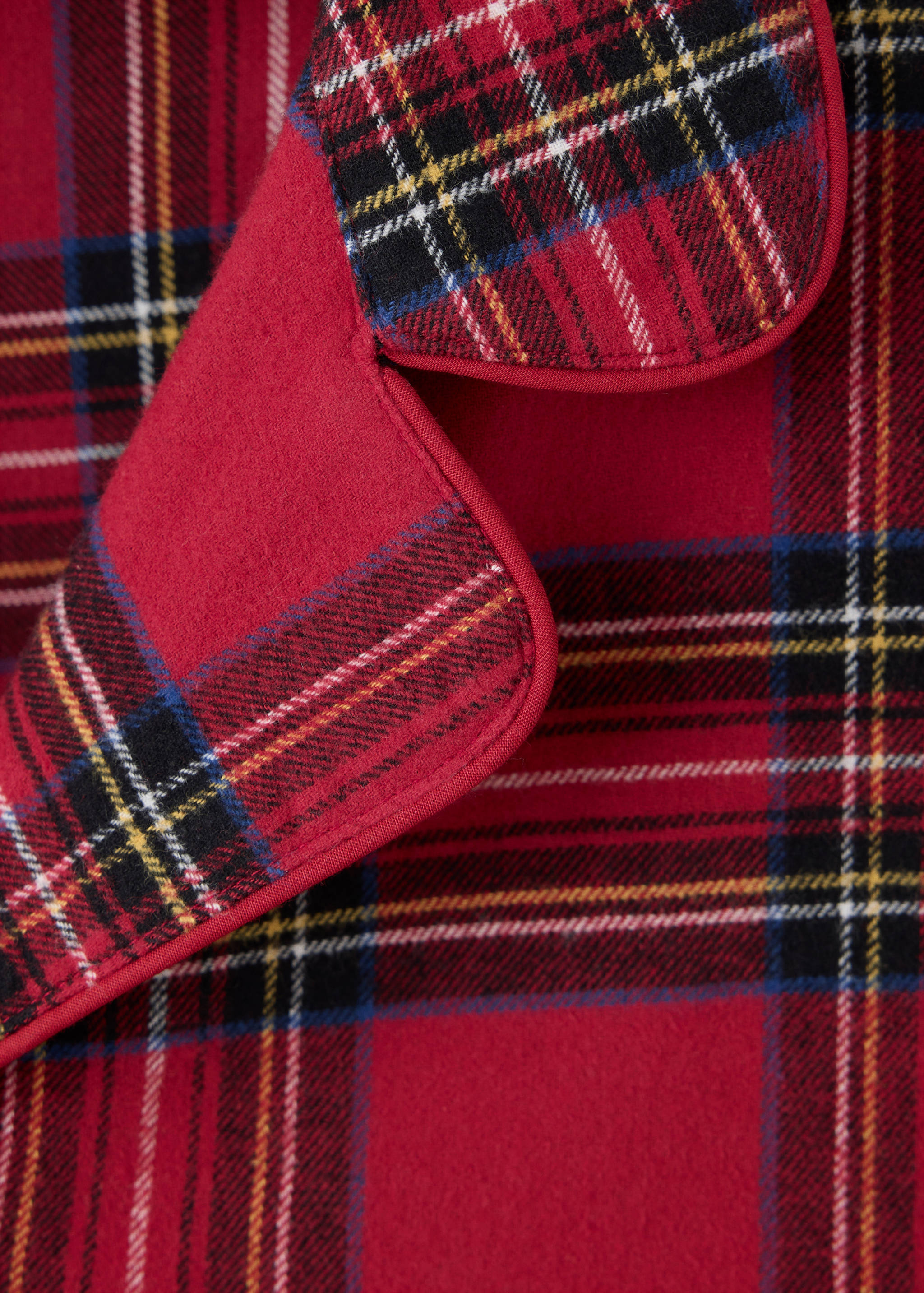 Close-up of red tartan plaid pajama collar with piping detail.