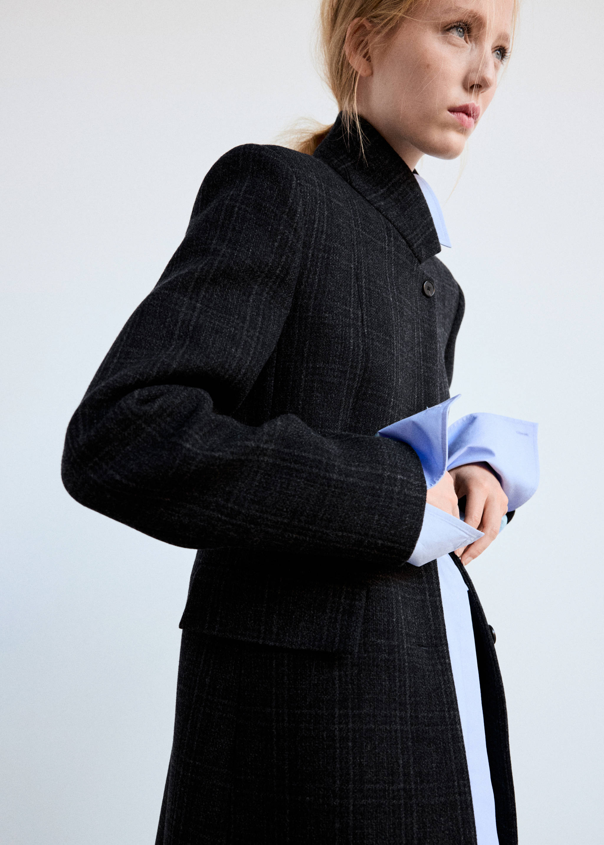Dark grey plaid coat with high collar worn over a blue shirt