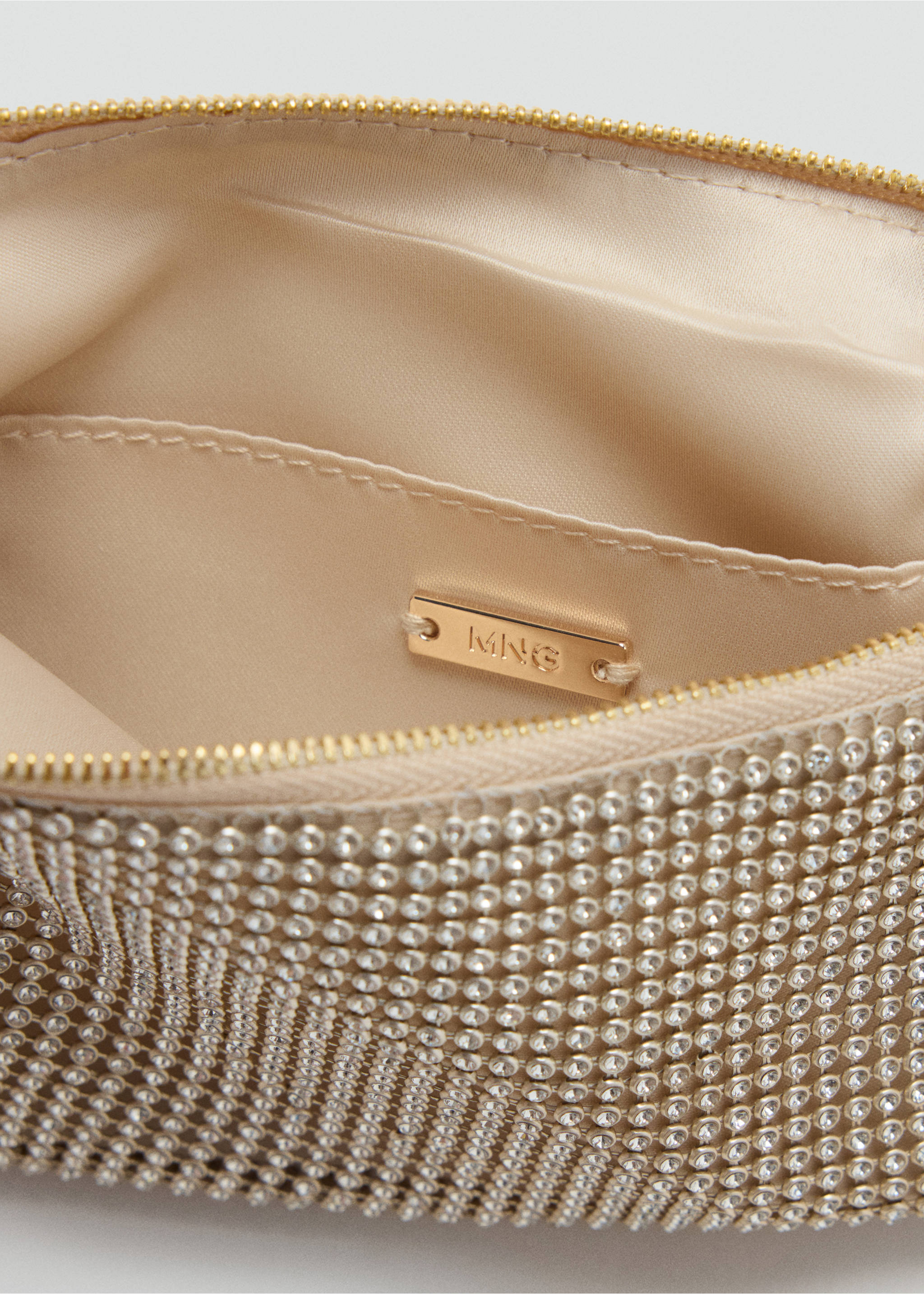 Close-up of a rhinestone handbag interior with lining and gold-tone brand plaque., Gold. Ref: 37099113-00.