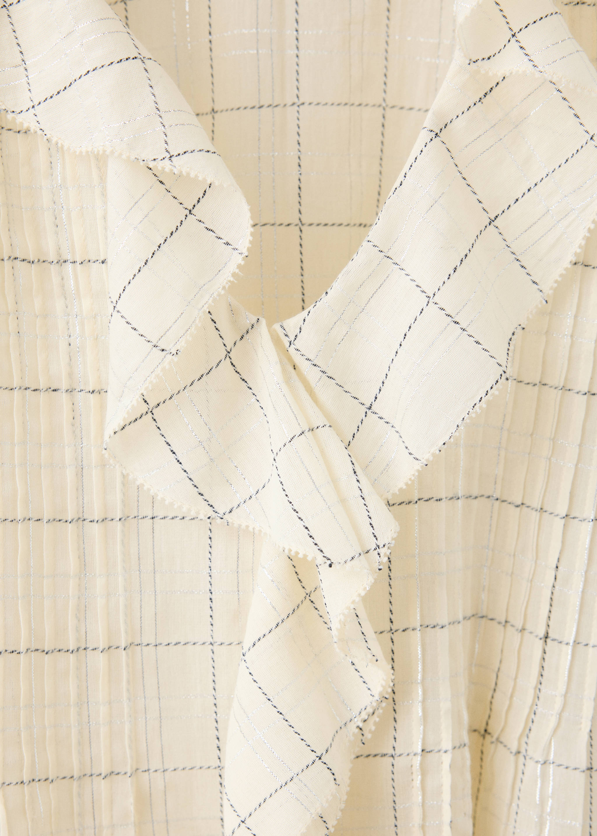 Blusa crema con estampado de cuadros metalizados y cuello con volantes.