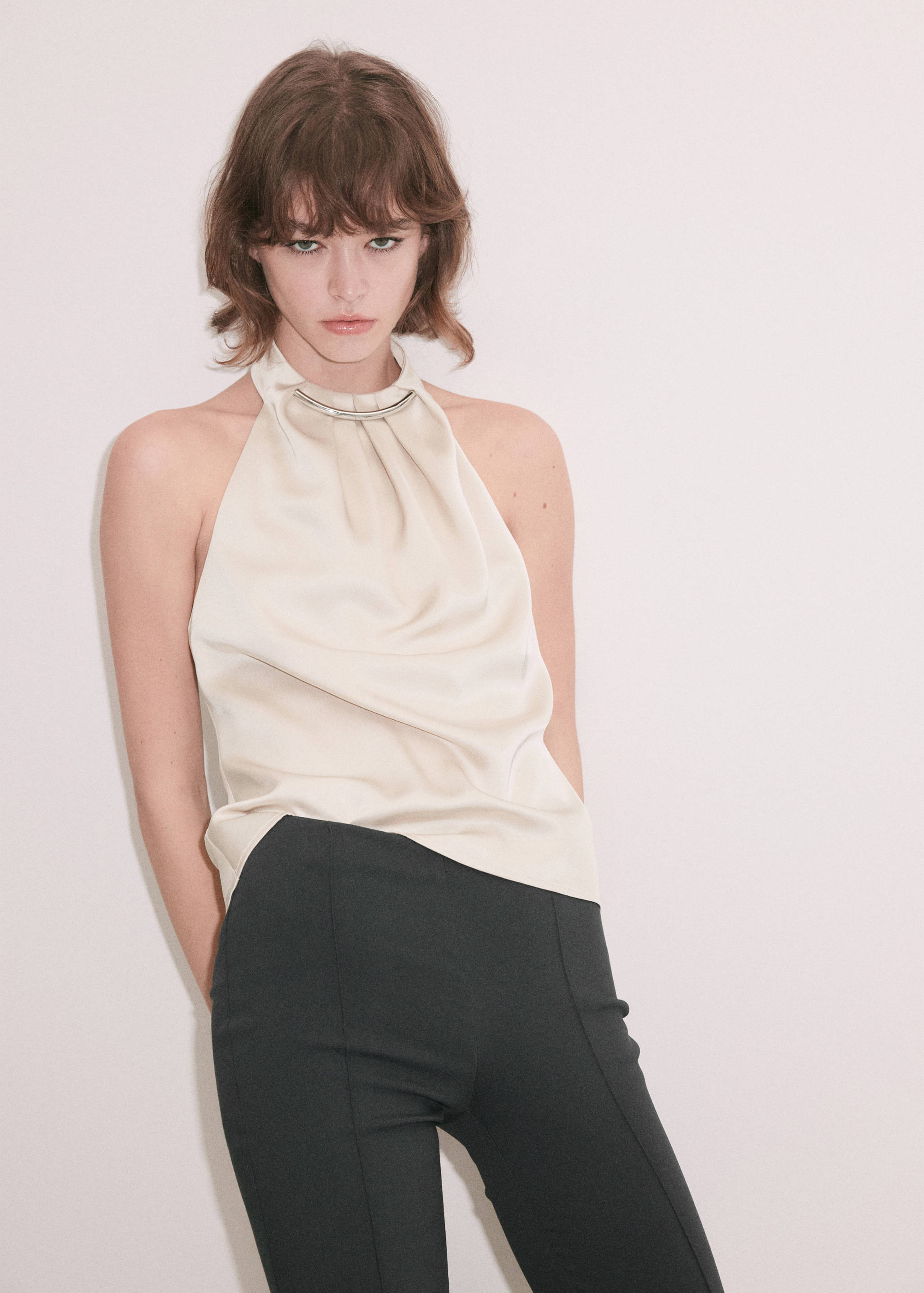 Off-white halter top with a high collar and metallic bar detail.