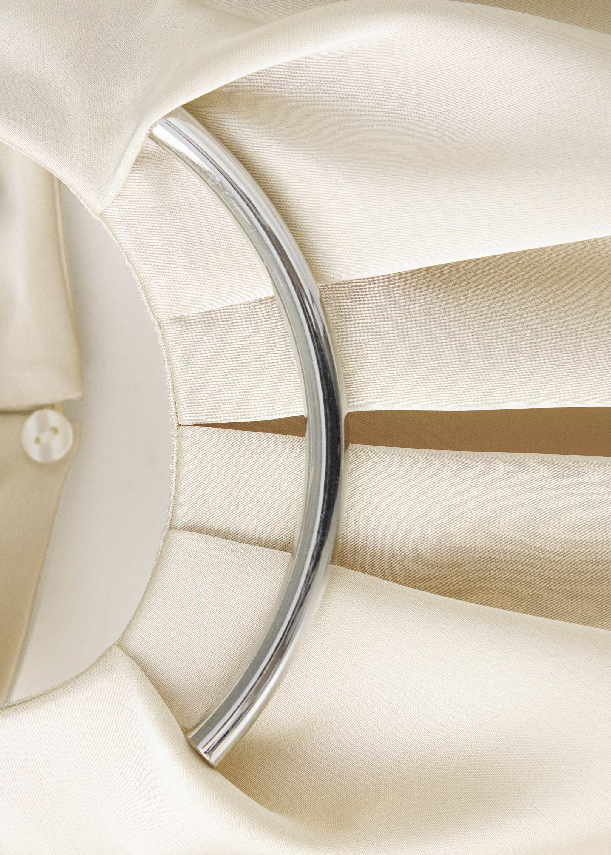 Cream top detail featuring a curved metallic neck ring.