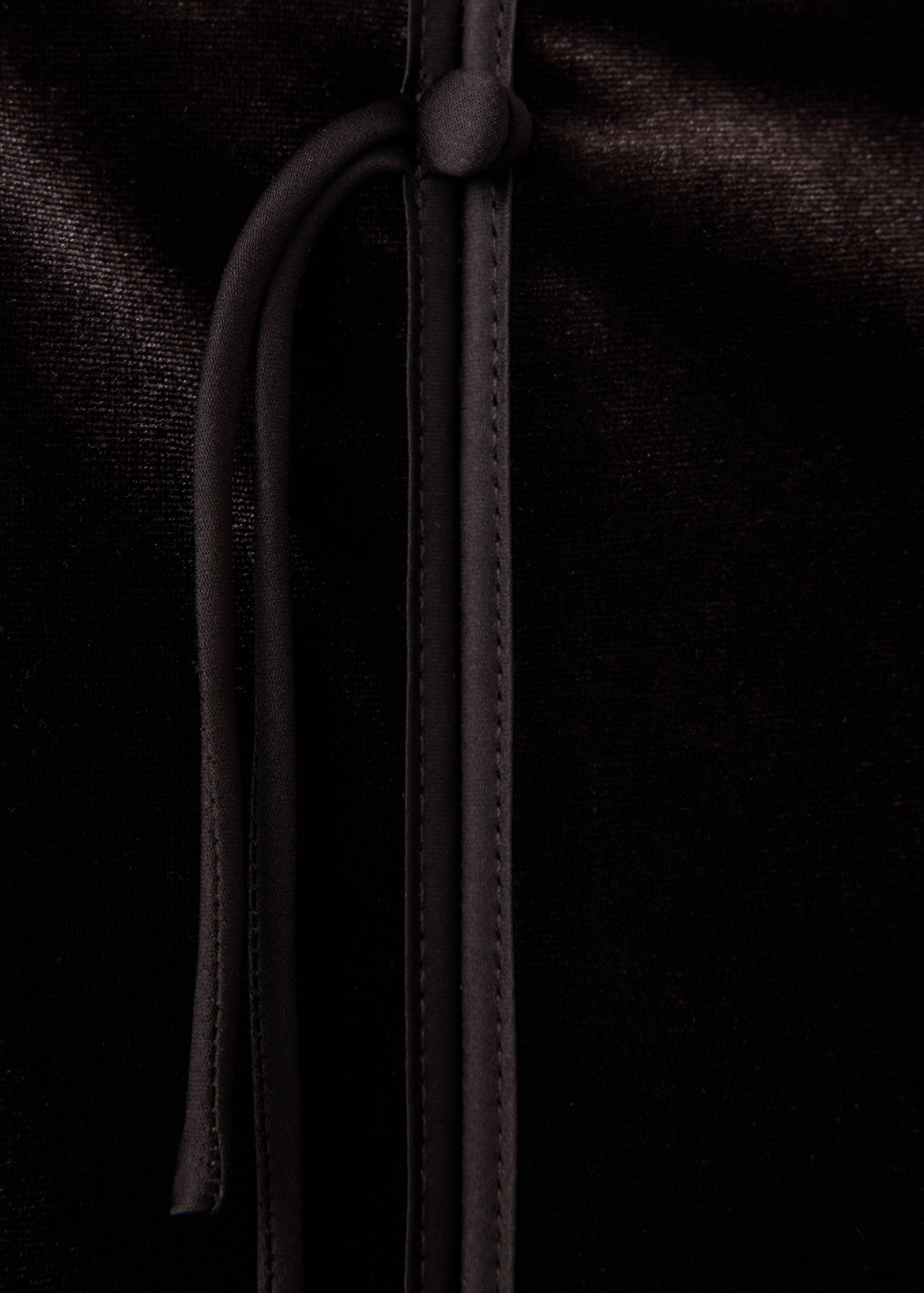 Close-up of a dark brown velvet skirt with a fastening detail.