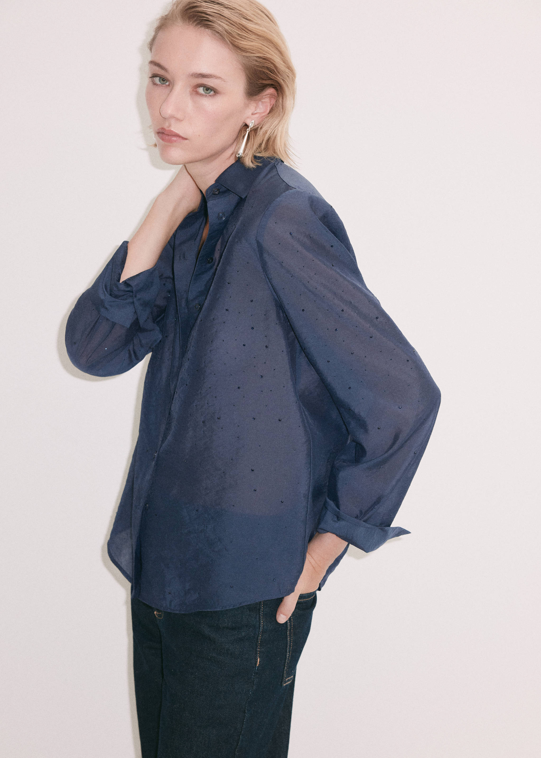 Navy blue button-down shirt with long sleeves, classic collar, and small dark embellishments.