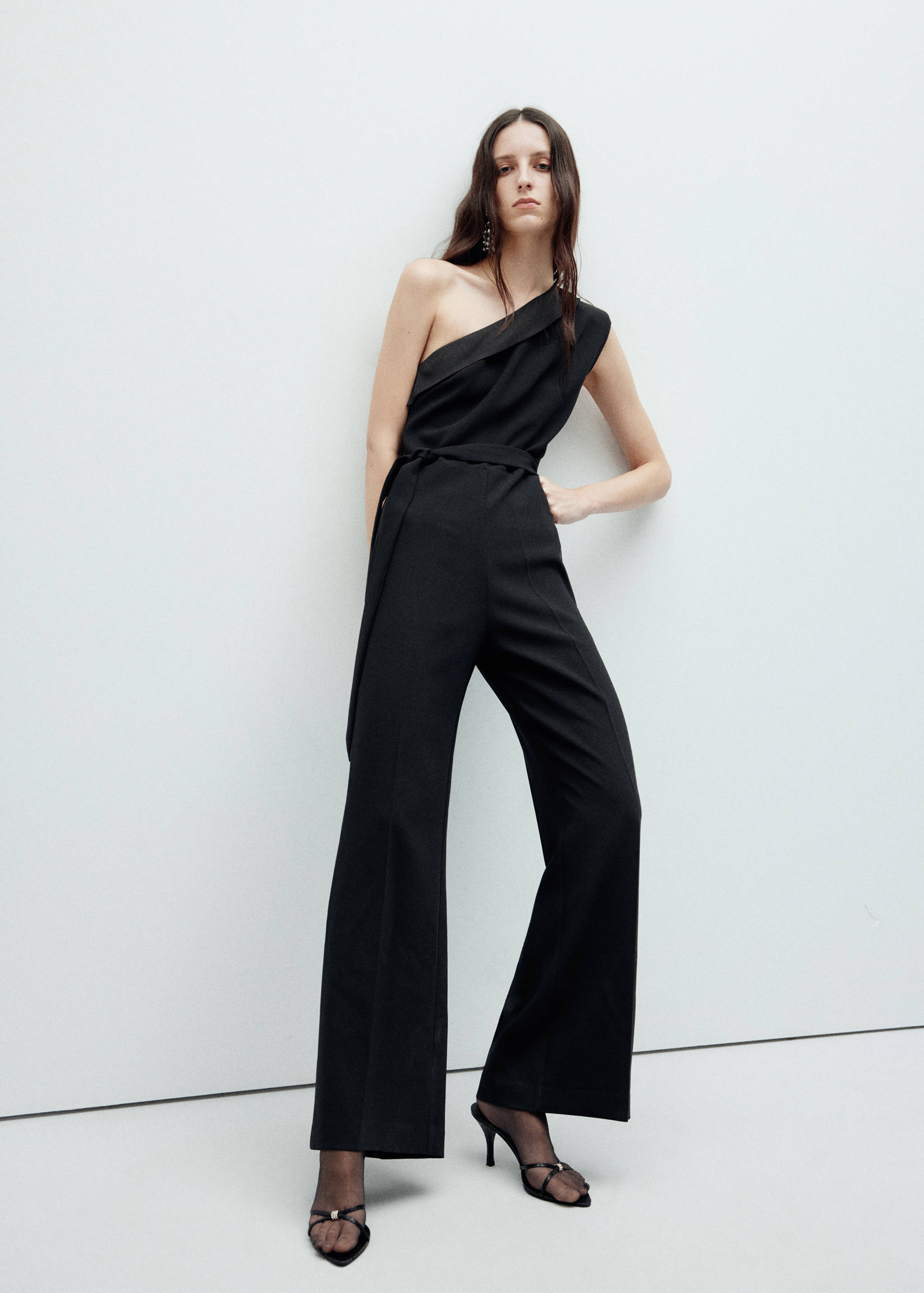 Black asymmetric one-shoulder jumpsuit with a fabric belt.