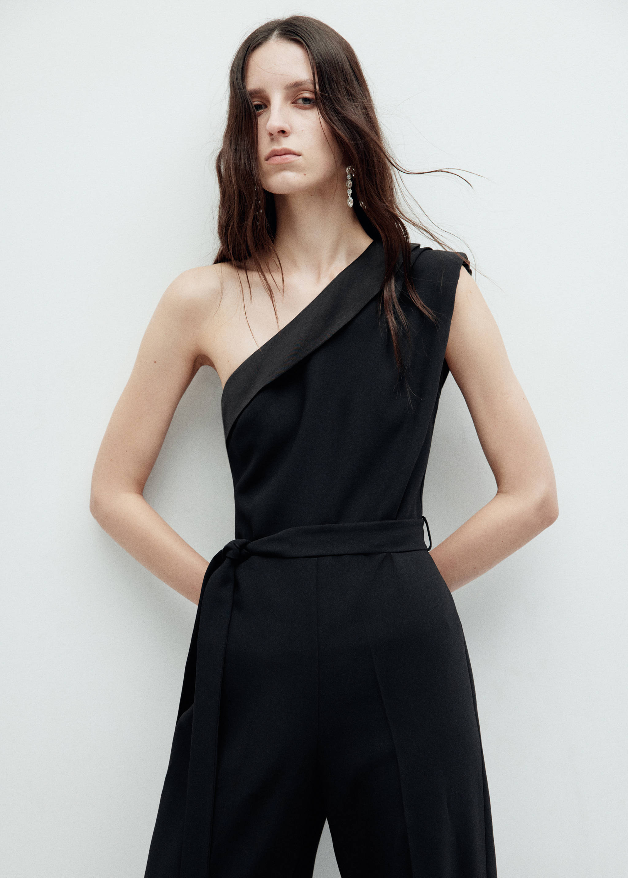 Black one-shoulder jumpsuit with an asymmetric draped neckline and tie belt.