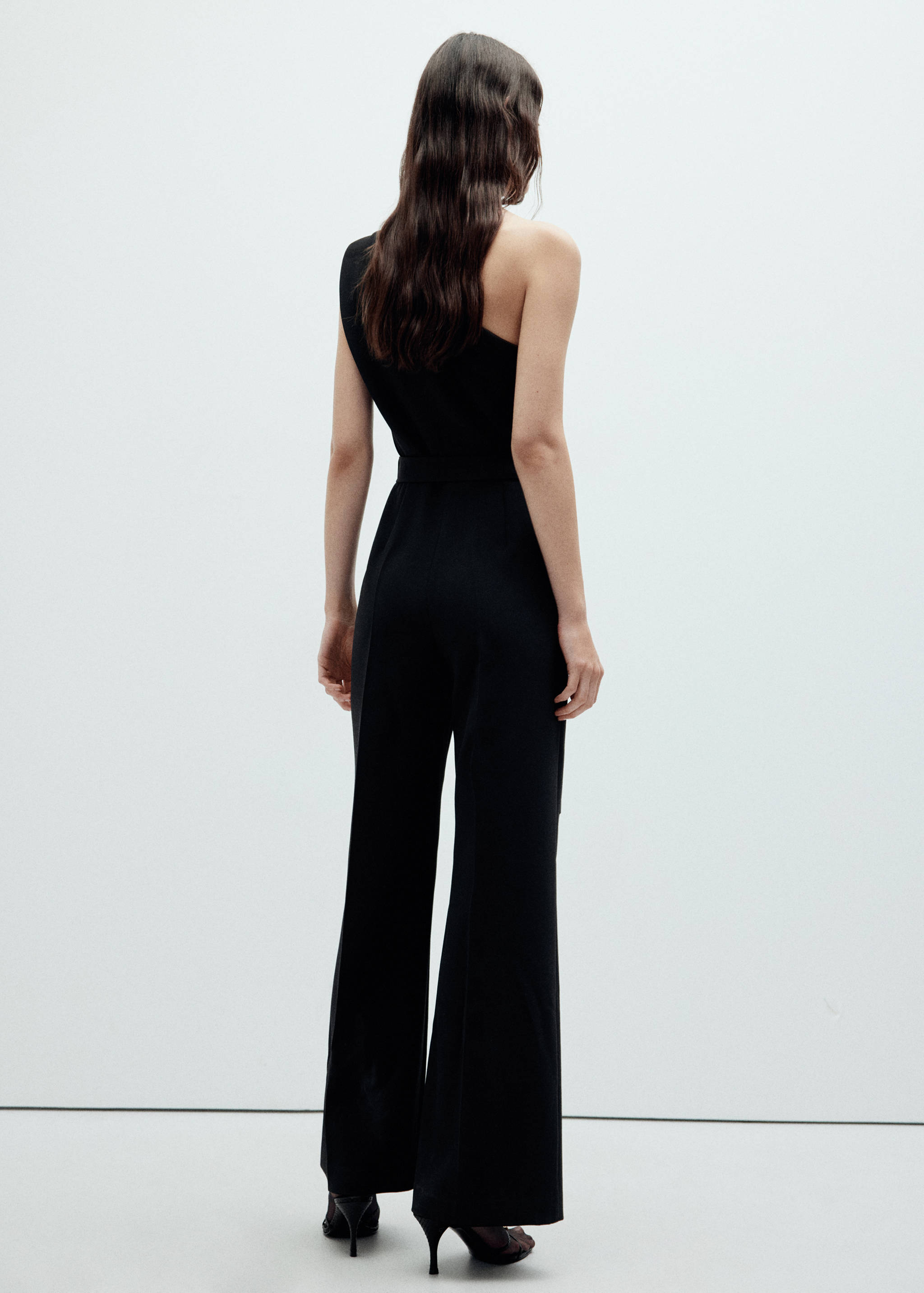Back view of a black one-shoulder jumpsuit with long straight trousers.