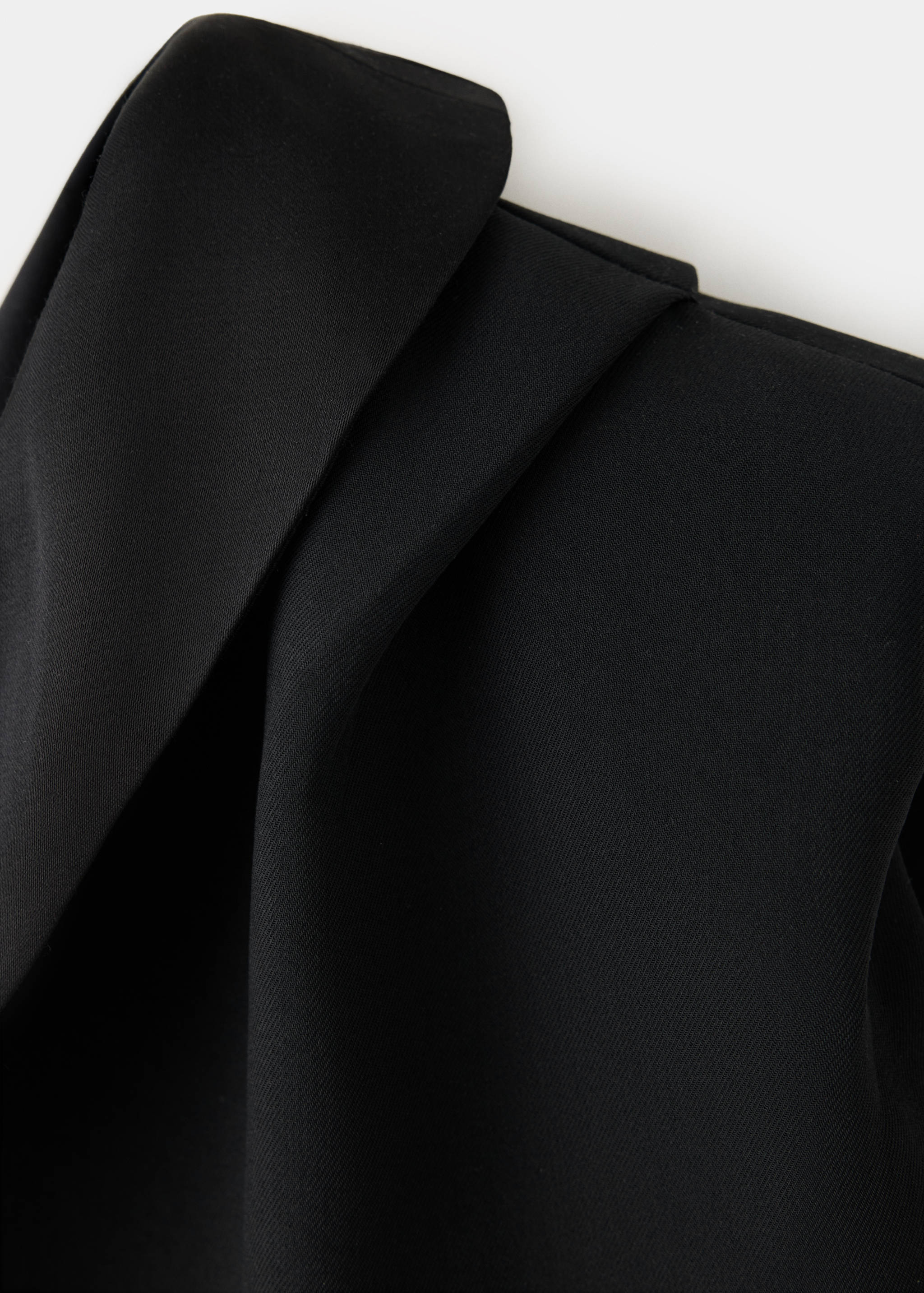 Black jumpsuit fabric detail showing smooth texture.