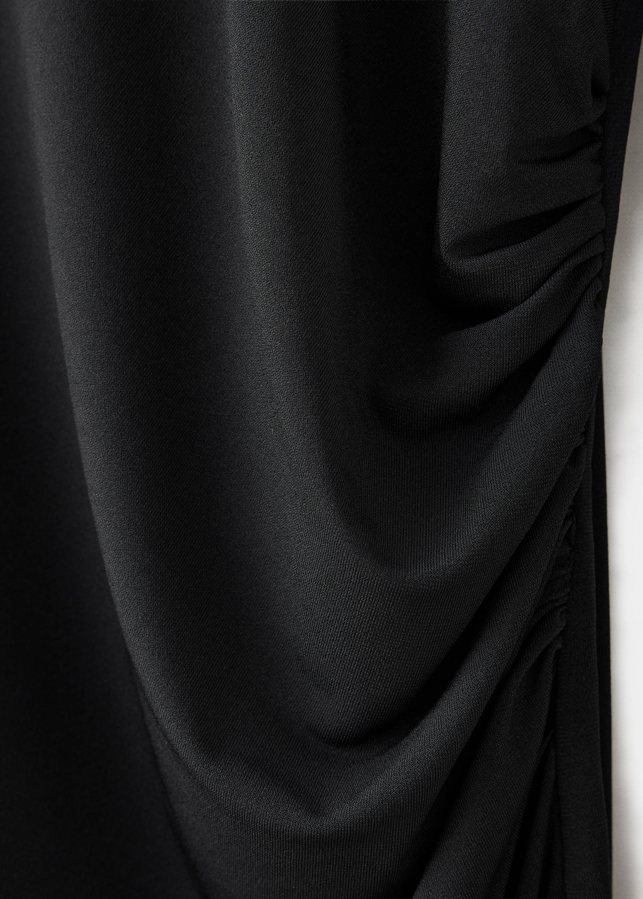Close-up of a black dress with gathered ruching along the side.