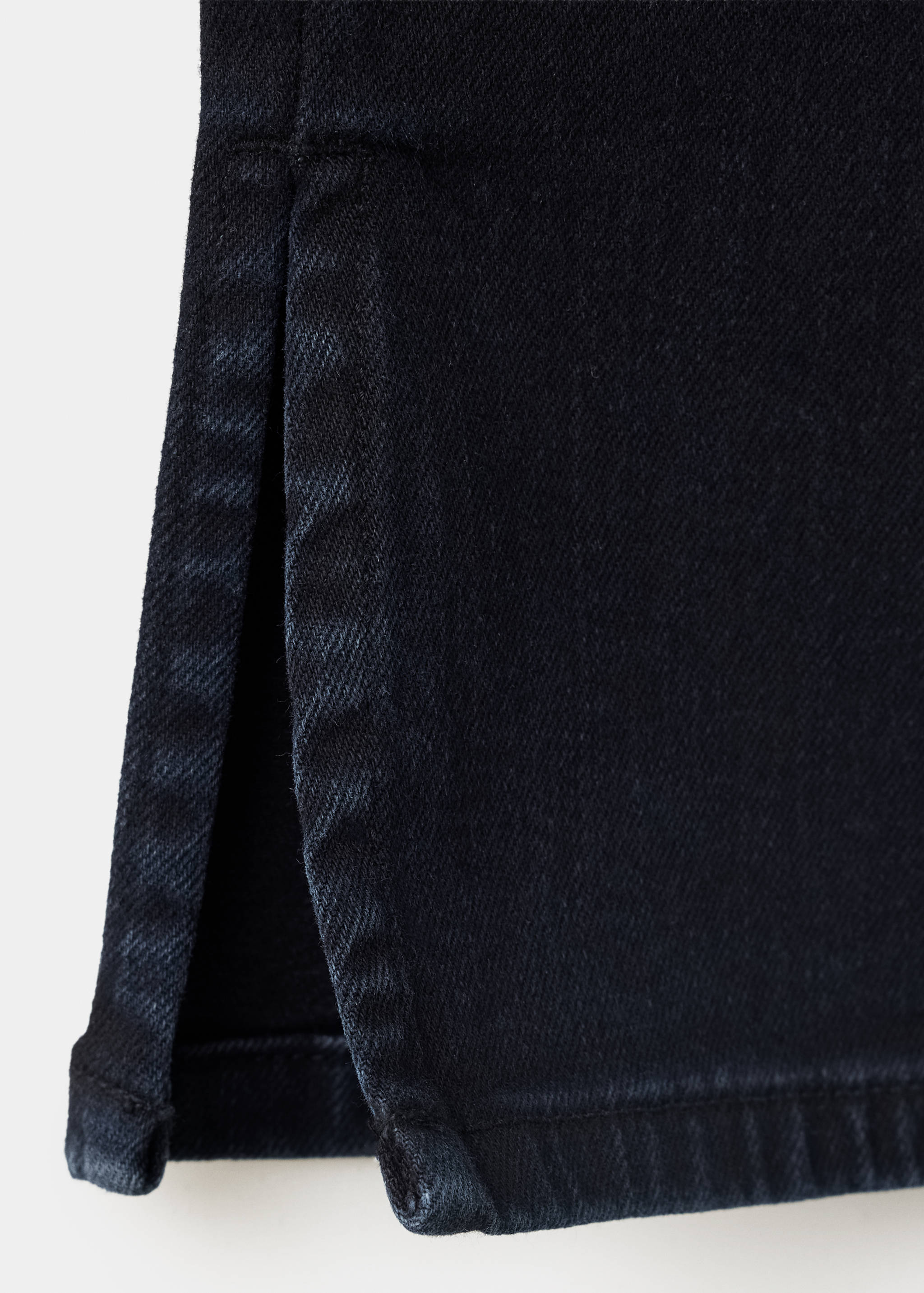 Dark blue denim trousers hem detail with a side slit.