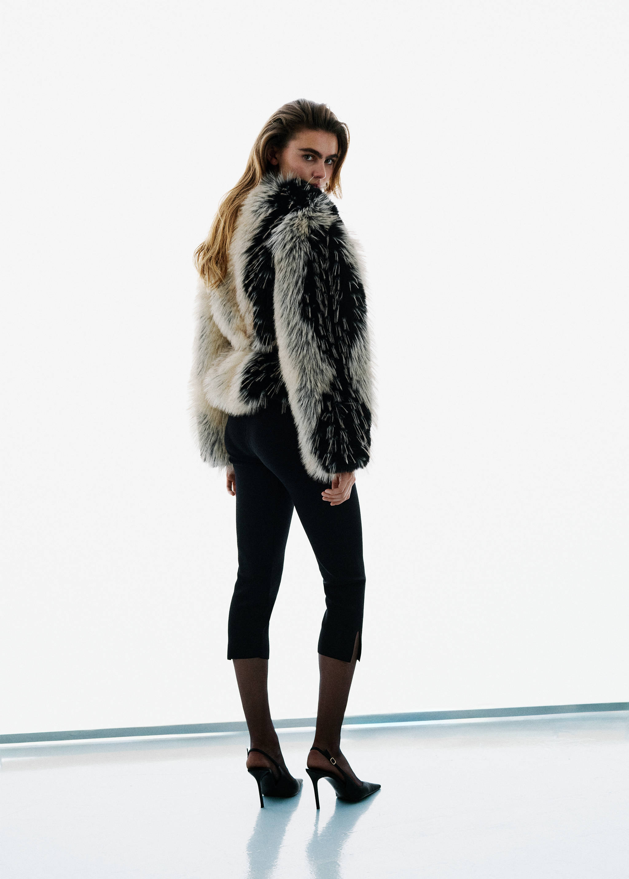 Black trousers worn from the back with a black and white faux-fur jacket.