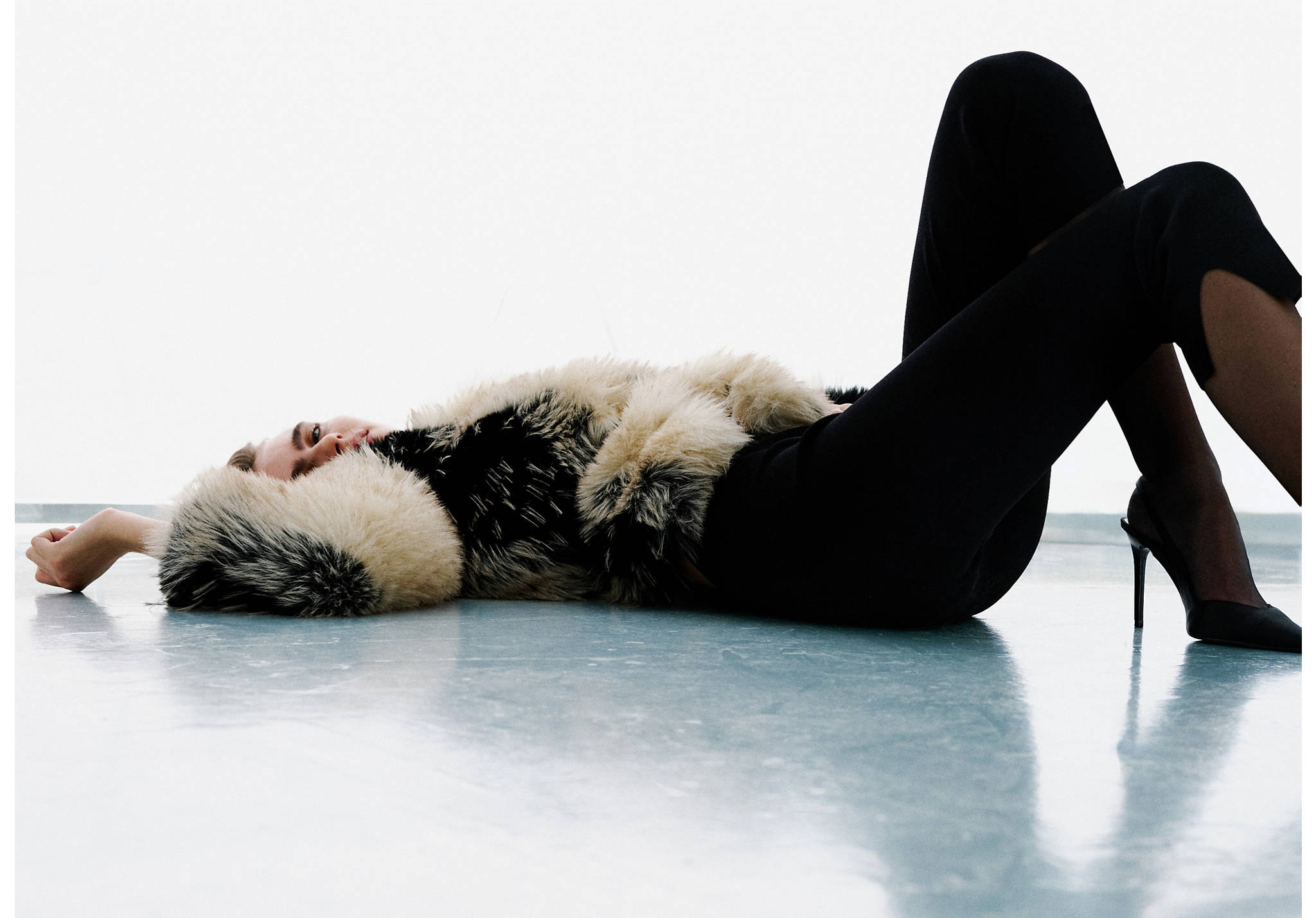 Black trousers worn by a model reclining on the floor.
