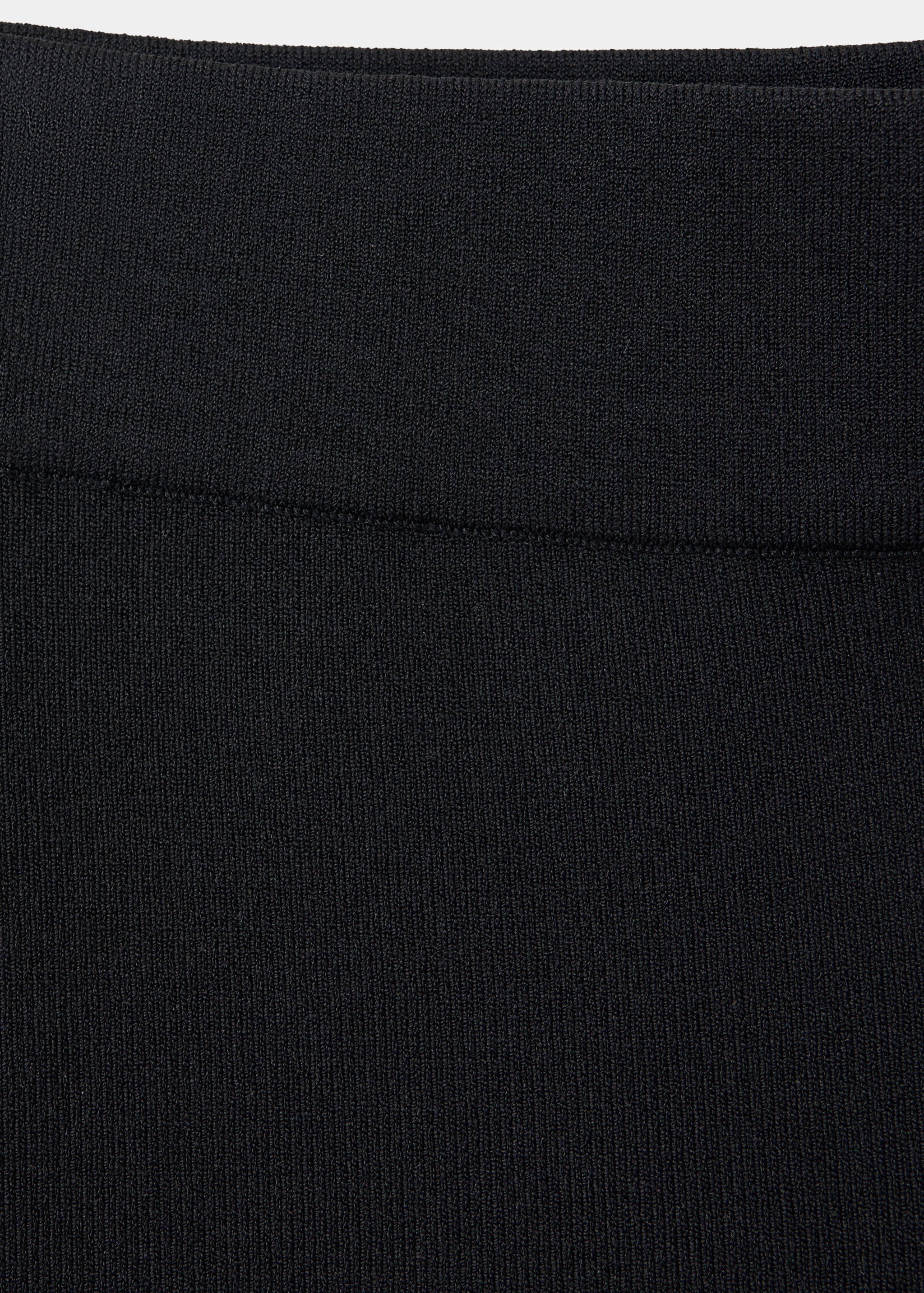 Close-up of black knitted trousers detail.